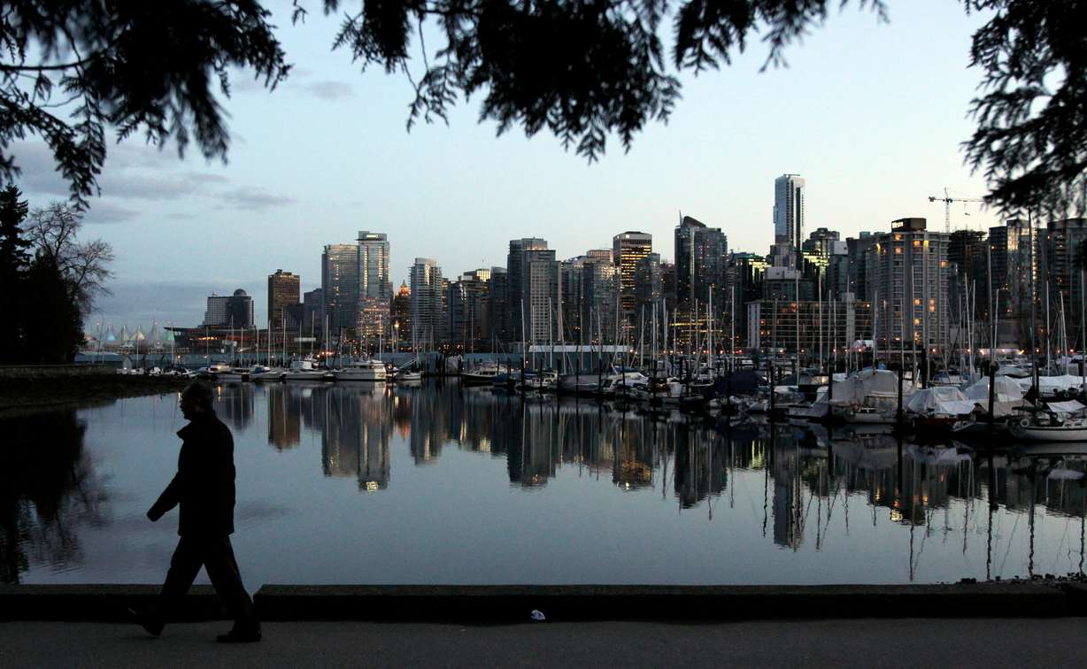 A man walks in Stanley Park as the skyline of Vancouver is reflected in water in Vancouver, British Columbia, Feb. 5, 2010. Vancouver announced its push for an MLB team last month.