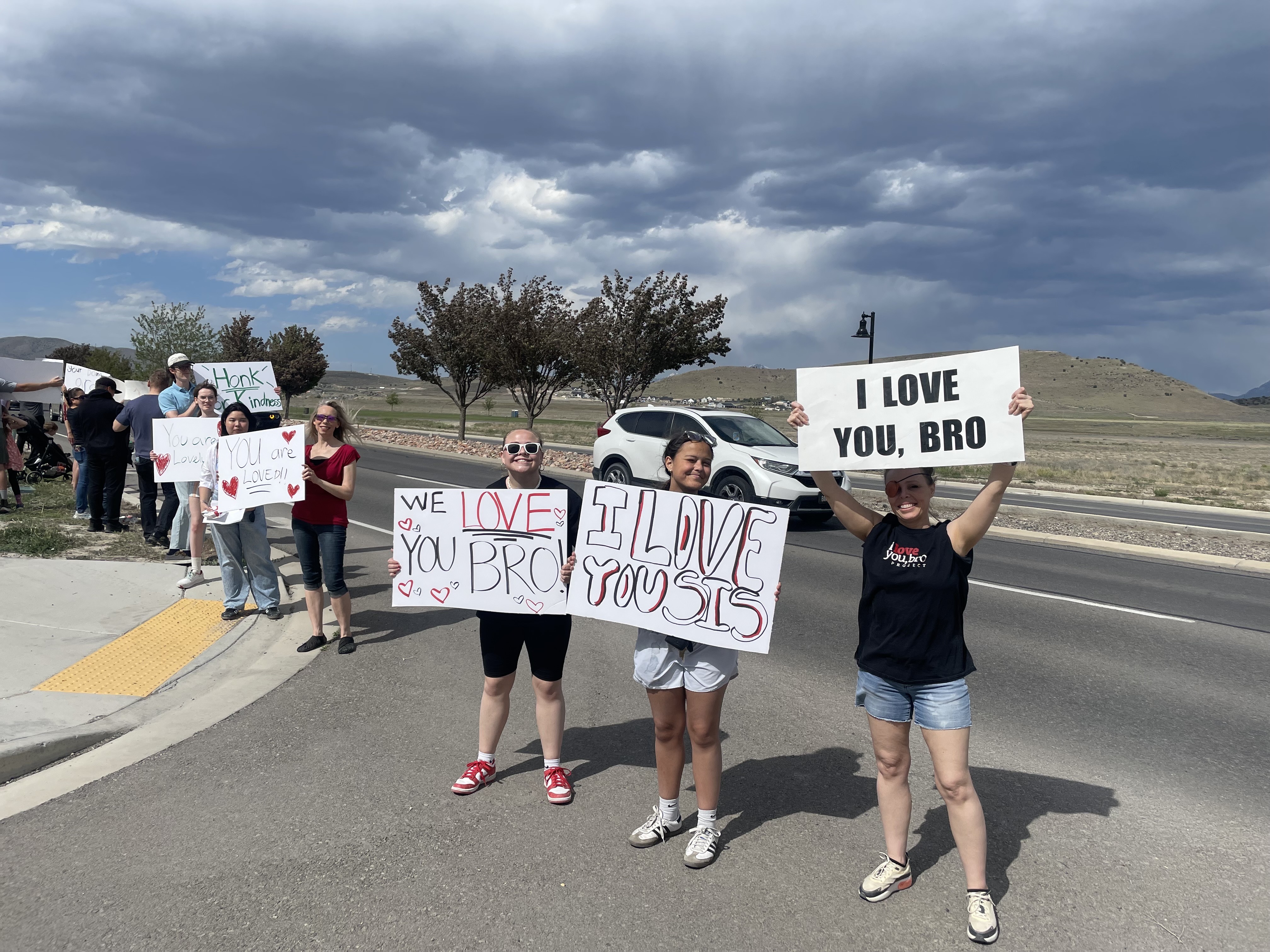 People hold signs with positive messages during the motivational mile in Eagle Mountain, May 22, 2025. The event is set to take place for a second year on June 6.