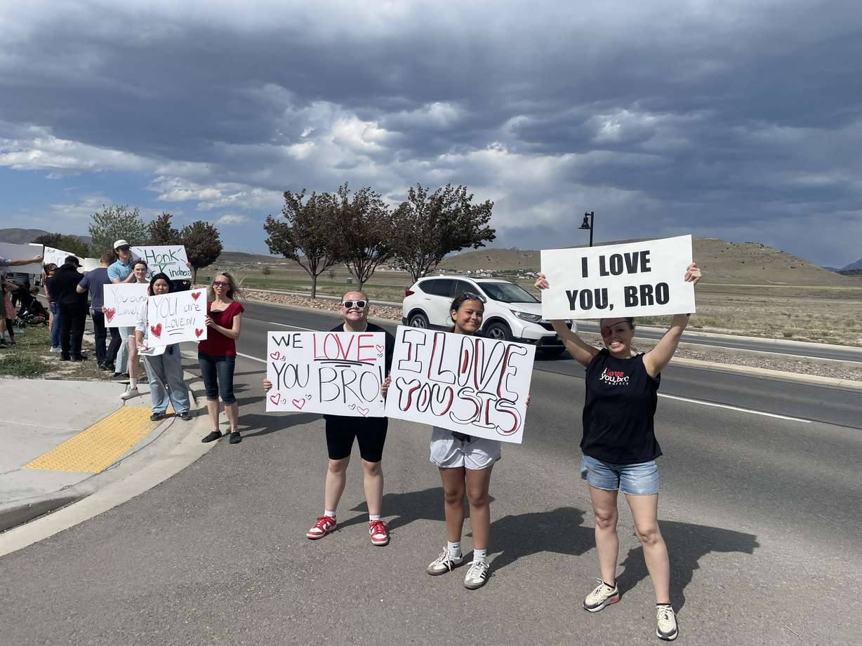 People hold signs with positive messages during the motivational mile in Eagle Mountain, May 22, 2025. The event is set to take place for a second year on June 6.