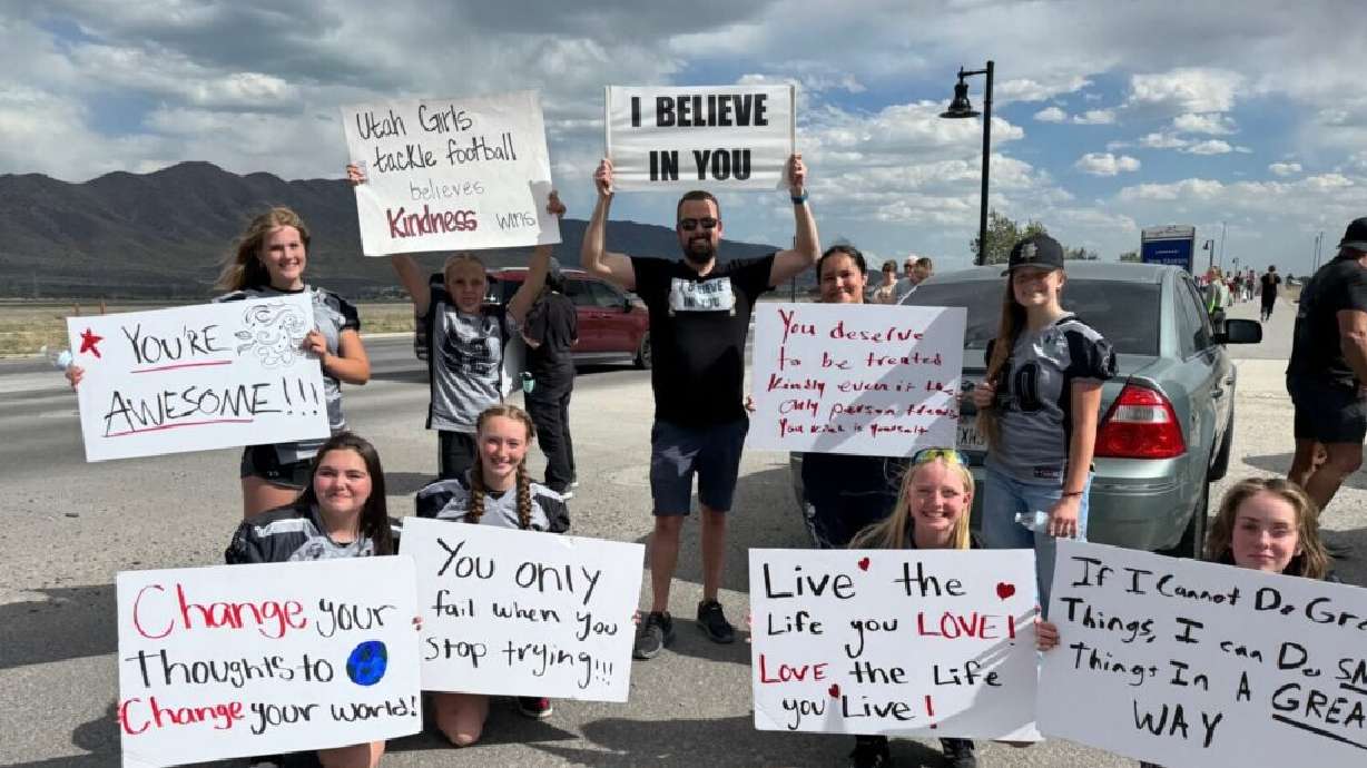 People hold signs with positive messages during the motivational mile in Eagle Mountain on May 22, 2025. The event is set to take place for a second year on June 6.