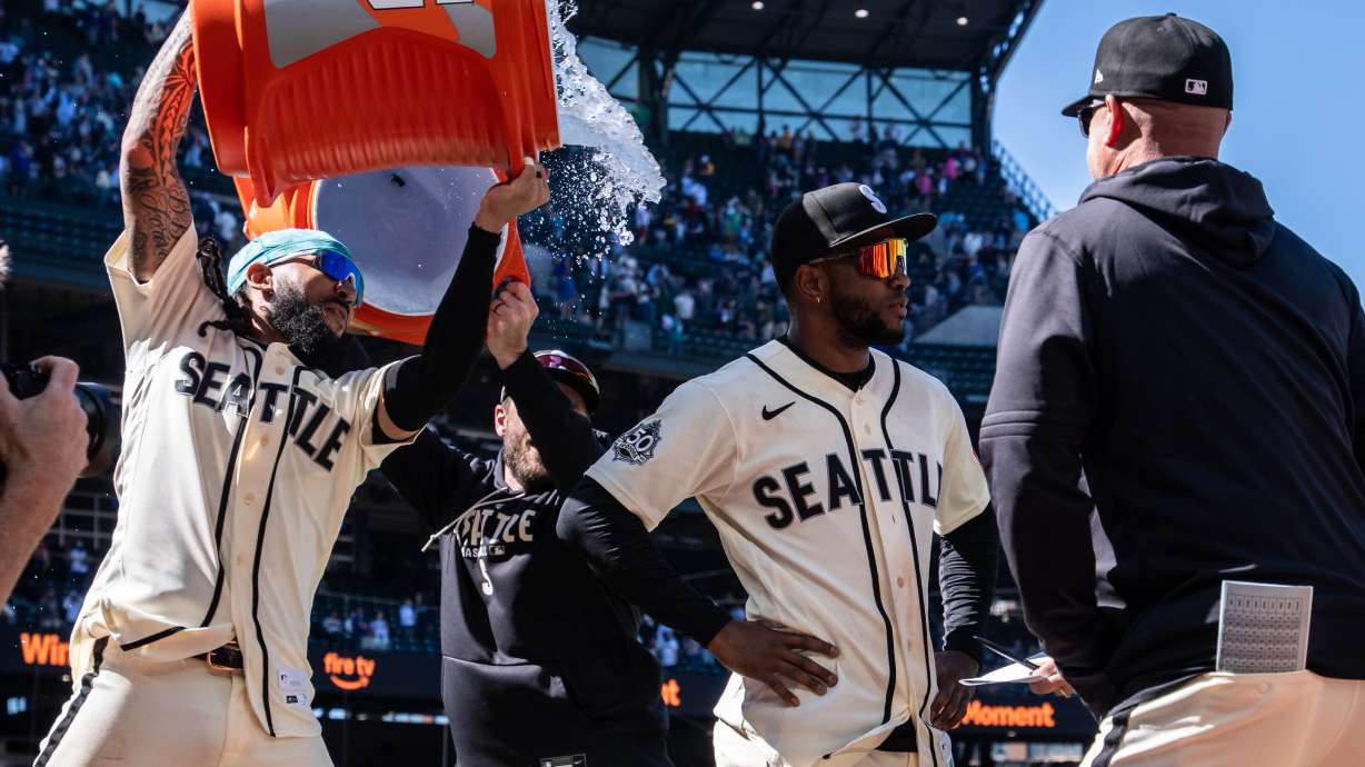 Seattle Mariners' J.P. Crawford, left, douses Victor Robles, second from right, after a baseball game against the Arizona Diamondbacks, Sunday, May 31, 2026, in Seattle.