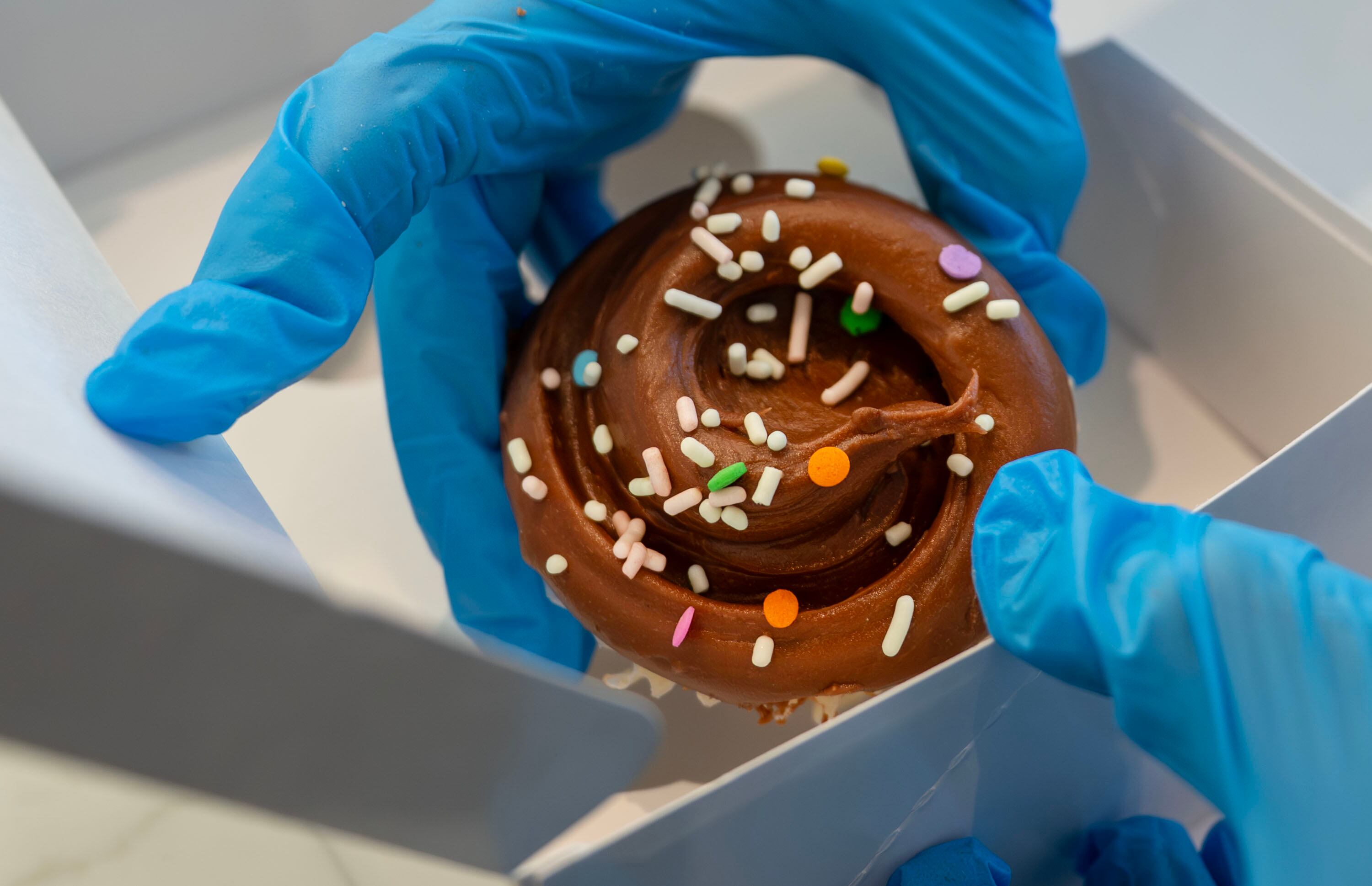 A worker places a cupcake in a to-go box at Magnolia Bakery as it opens in Holladay on Monday.