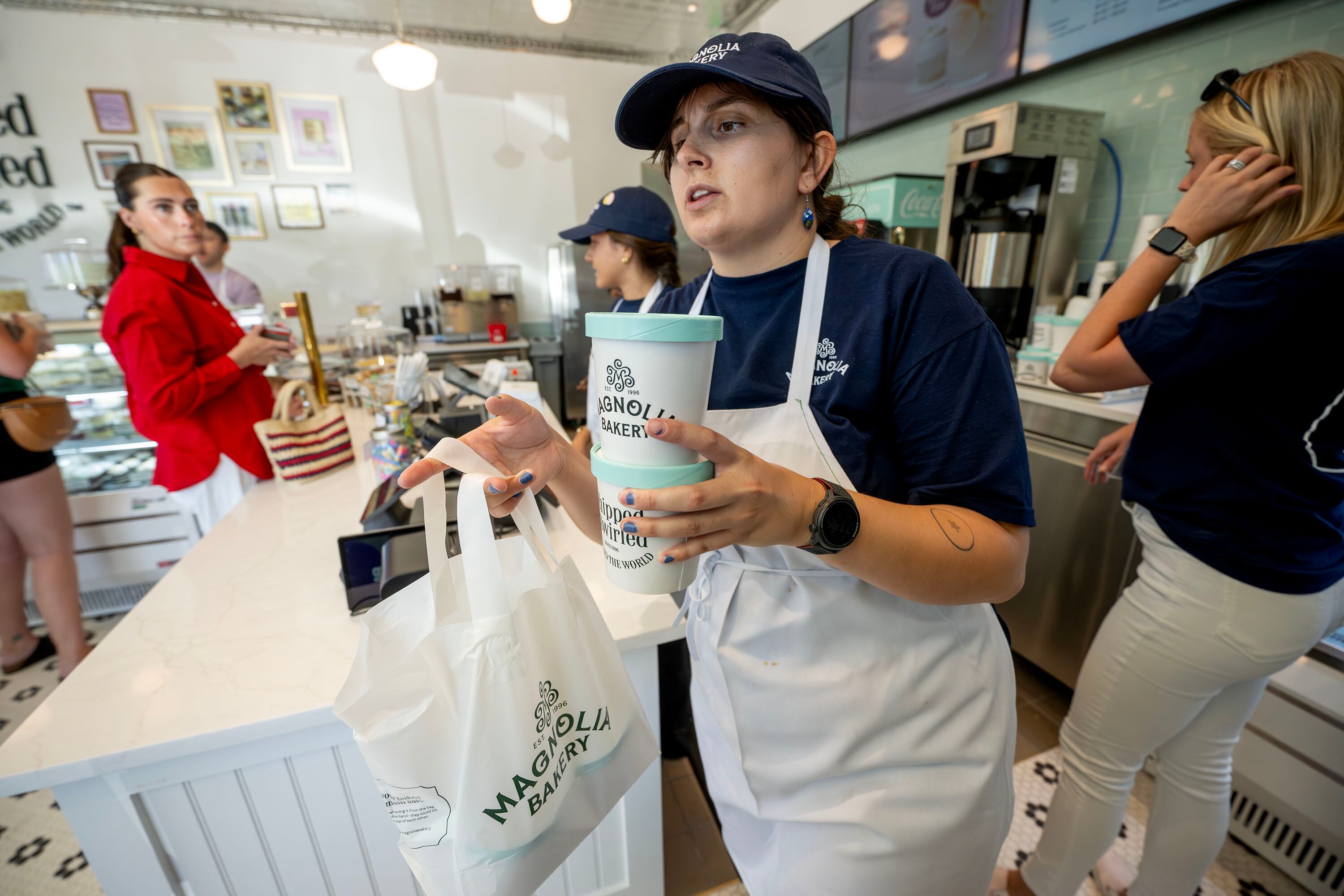 A worker carries items to a customer as Magnolia Bakery opens in Holladay on Monday.
