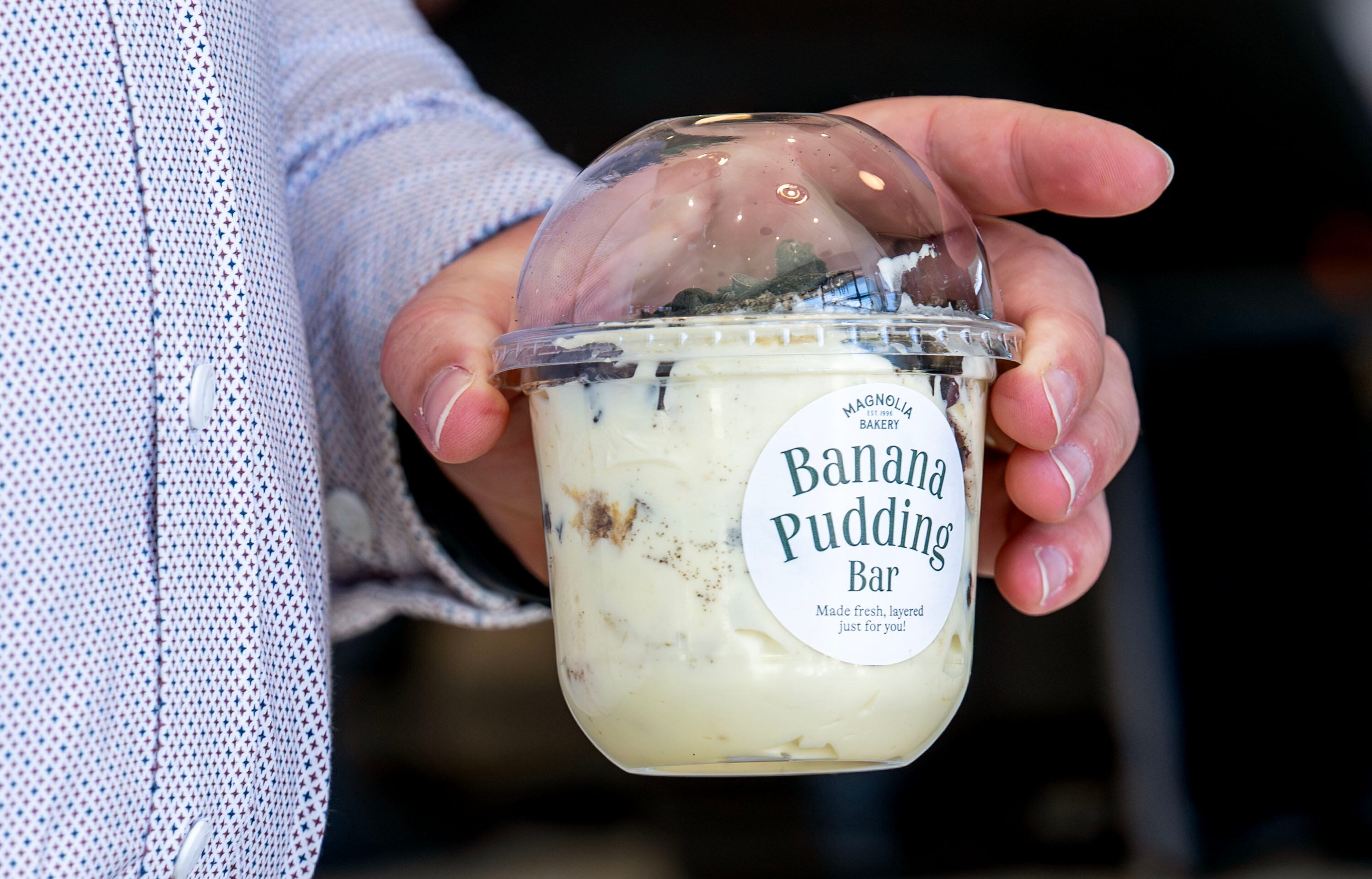 A customer carries a banana pudding container out as Magnolia Bakery opens in Holladay on Monday.