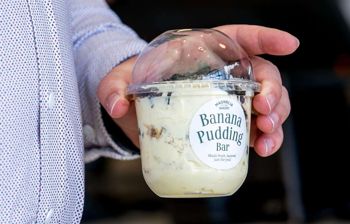 A customer carries a banana pudding container out as Magnolia Bakery opens in Holladay on Monday.