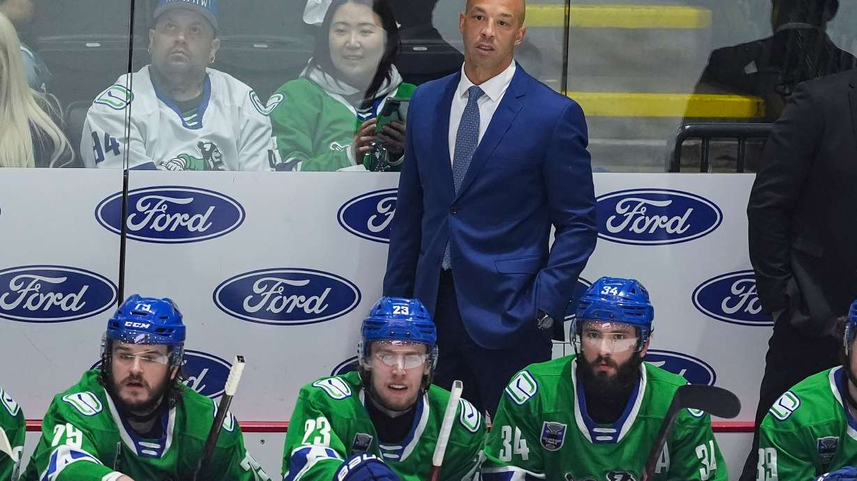 FILE -Abbotsford Canucks' head coach Manny Malhotra stands on the bench behind Sammy Blais, front left to right, Jonathan Lekkerimaki and Phillip Di Giuseppe during the first period in Game 5 of the AHL hockey Calder Cup Final against the Charlotte Checkers, in Abbotsford, British Columbia, June 21, 2025.