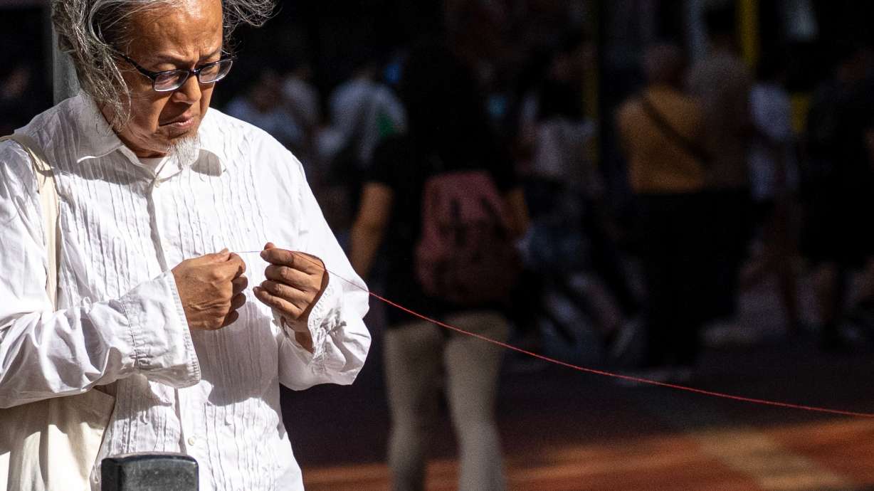 Artist Sanmu Chen displays a red thread as he performs on the street in the Causeway Bay area on the eve of the 37th anniversary of China's Tiananmen Square crackdown in Hong Kong, Wednesday.