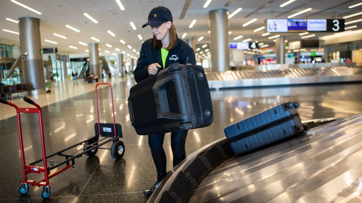 Jeanette Lee, co-founder and chief commercial officer of Bringit, demonstrates picking up luggage at Salt Lake City International Airport on Wednesday. The company provides an on-demand, same-day luggage delivery service.