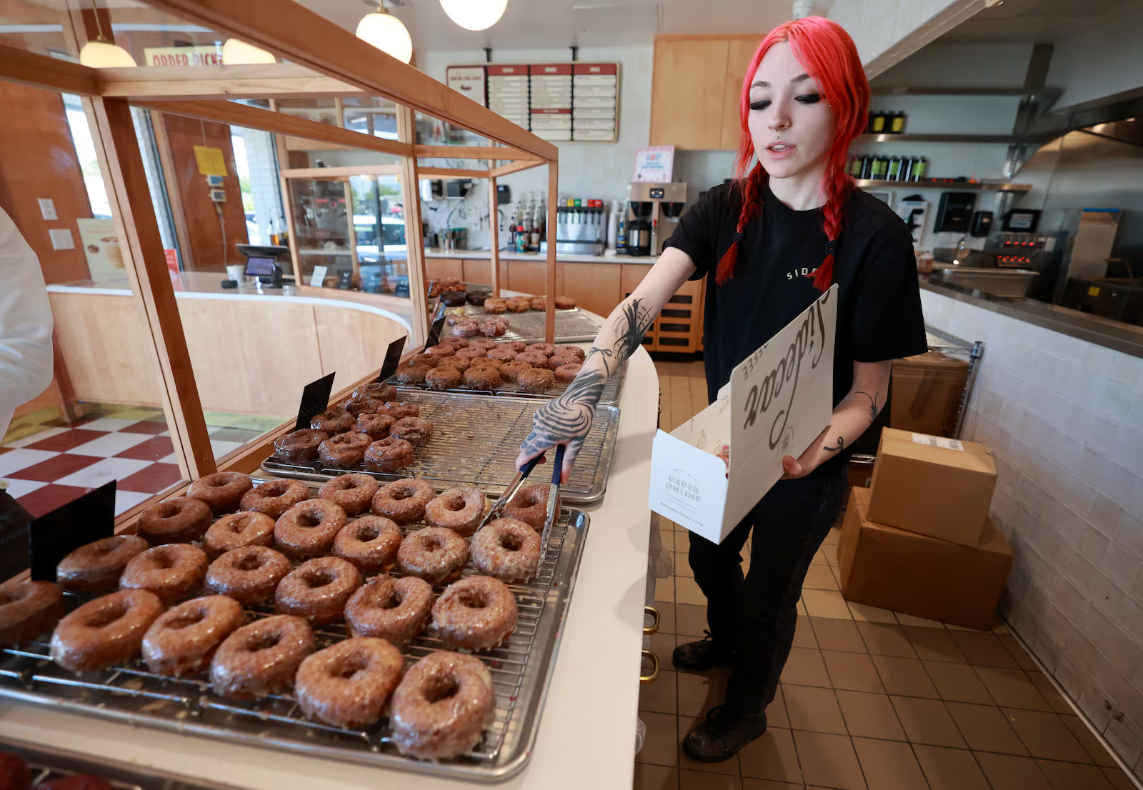 Lillianna Hoy boxes up doughnuts for a customer at Sidecar Doughnuts in Salt Lake City on Thursday. National Doughnut Day, which originated from the "Donut Lassies" during World War I, is being celebrated Friday nationwide.