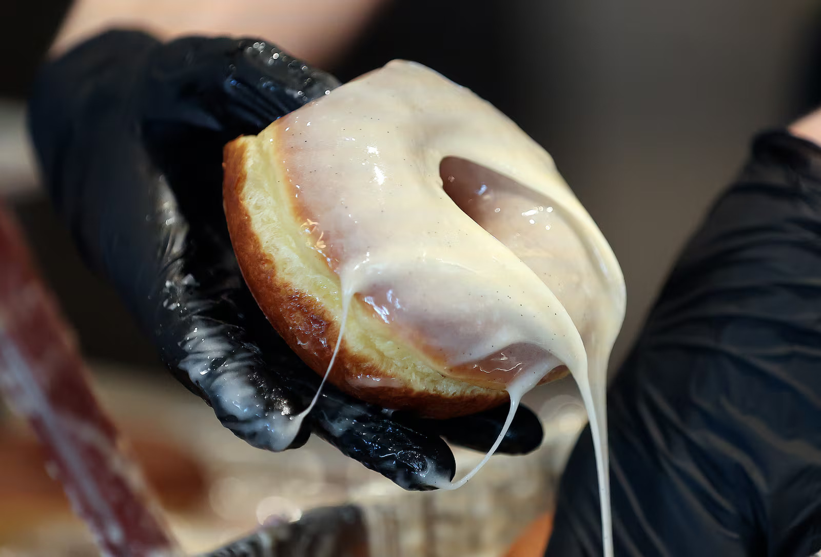 An employee glazes a doughnut at Sidecar Doughnuts in Salt Lake City on Thursday. The California-based shop is making rewards earners winners on National Doughnut Day on Friday.