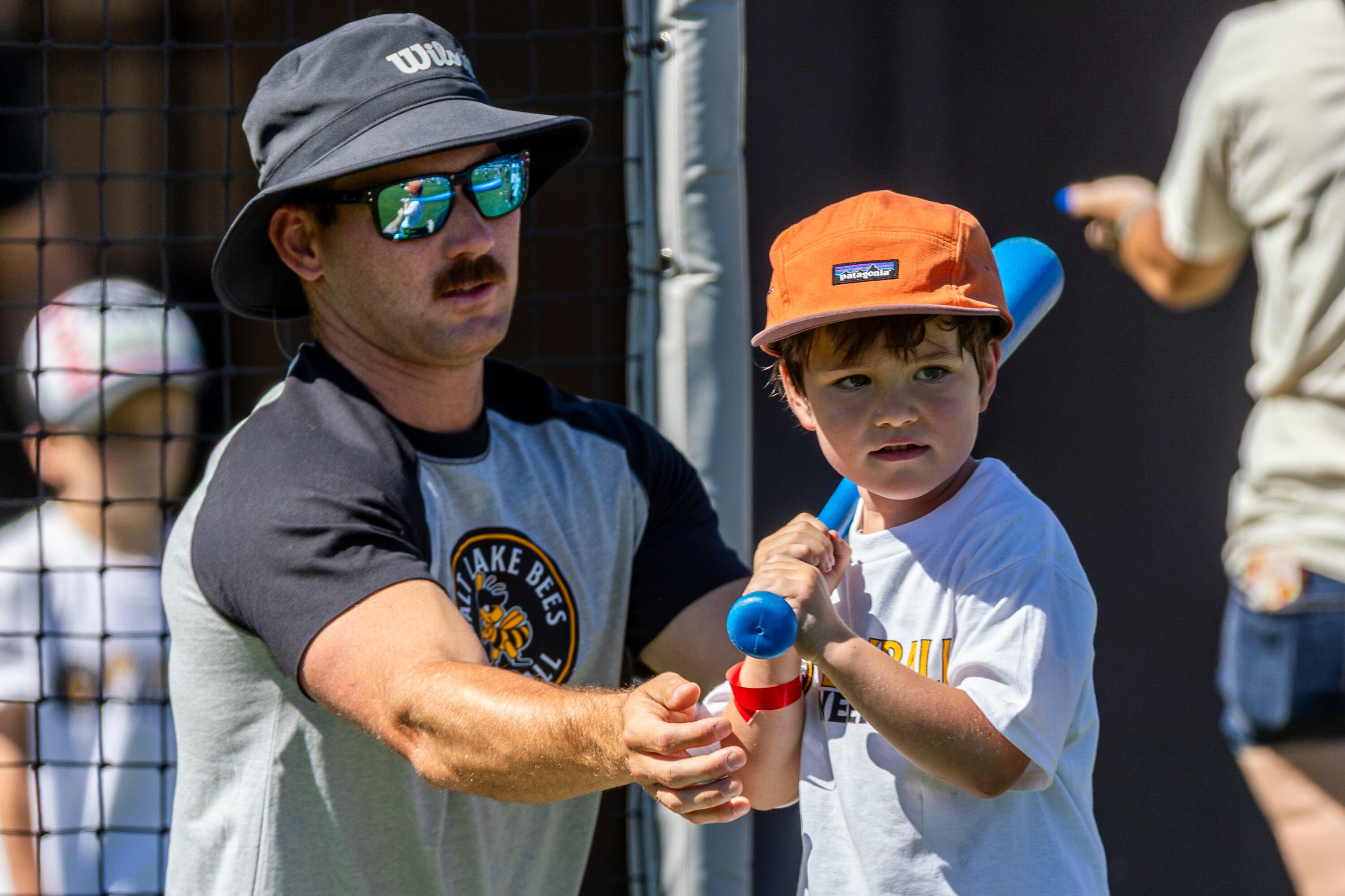 Salt Lake Bees catcher Zach Humphreys helps position Jayden Park, 5, of Midvale, at bat as they prepare for a pitch as part of activities during a kick-off event for Utah Youth Sports Giving Day held at The Ballpark at America First Square in South Jordan on Friday. The event looks to increase access for youth sports in the state.
