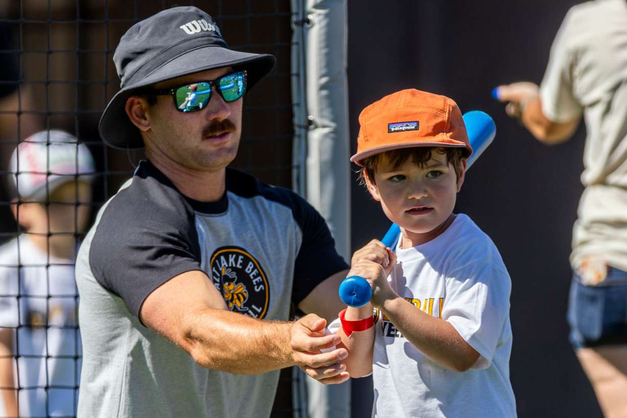 Salt Lake Bees catcher Zach Humphreys helps position Jayden Park, 5, of Midvale, at bat as they prepare for a pitch as part of activities during a kick-off event for Utah Youth Sports Giving Day held at The Ballpark at America First Square in South Jordan on Friday. The event looks to increase access for youth sports in the state.