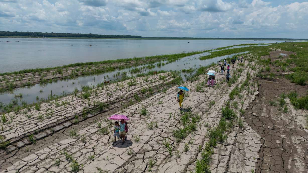 People walk through a part of the Amazon River that shows signs of drought in Santa Sofia, on the outskirts of Leticia, Colombia, Oct. 20, 2024.
