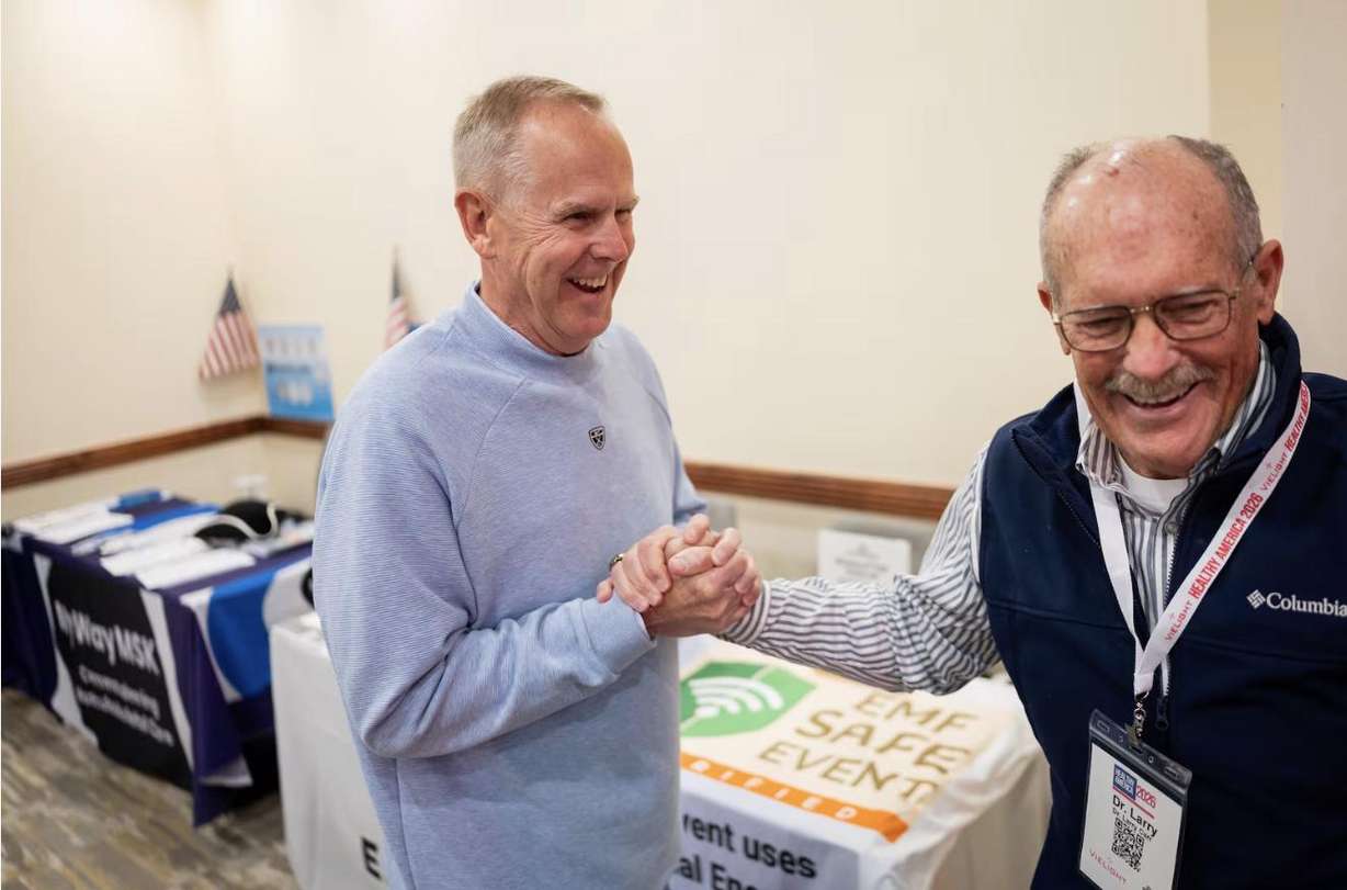 Former BYU and San Francisco 49ers football player Tom Holmoe, left, greets former BYU football player Larry Carr, right, before they speak about red light therapy treatment for CTE during the “Healthy America 2026 — Going for the Summit” conference at the Westgate Park City Resort & Spa in Park City on May 5.