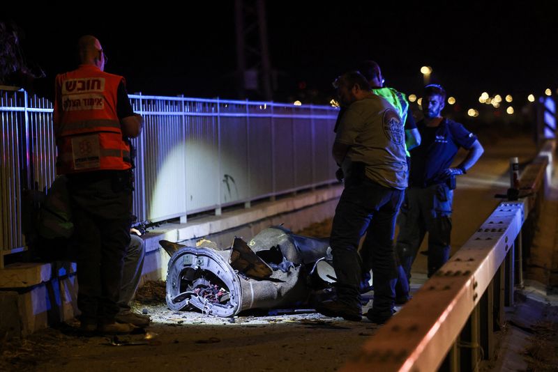 Israeli security and rescue personnel work next to a part of a projectile following a missile attack from Iran towards Israel in northern Israel, Sunday.