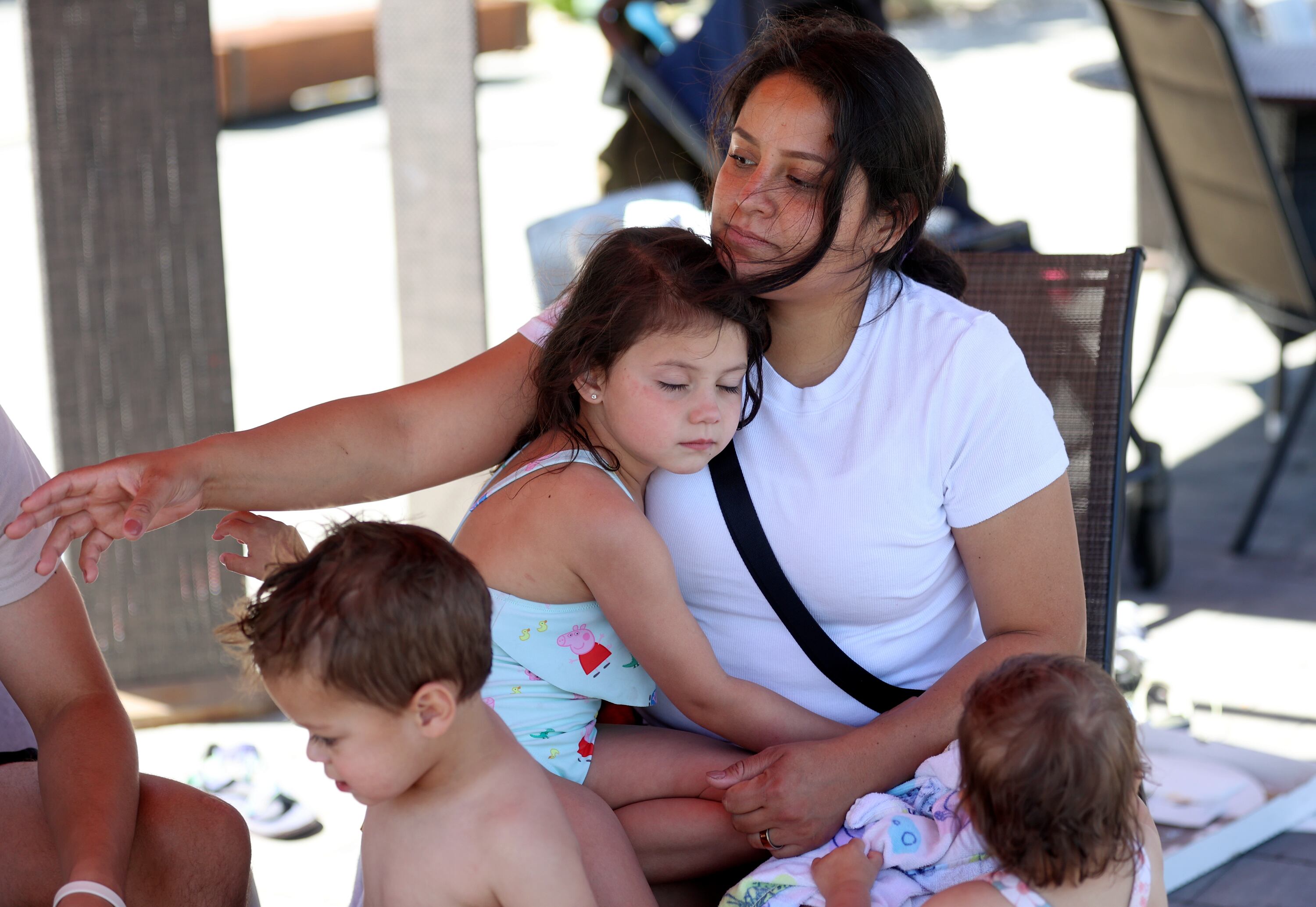 Annie Weese, 4, hugs her mother, Ada Weese, while taking a break from the splash pad at Millcreek Common in Millcreek on Thursday. Ada Weese says building close relationships with her children now through experiences like these is important.