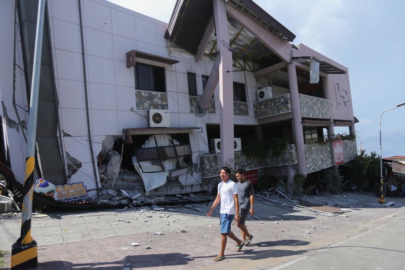 Residents pass by a collapsed structure after an earthquake in General Santos, Philippines, on Monday.