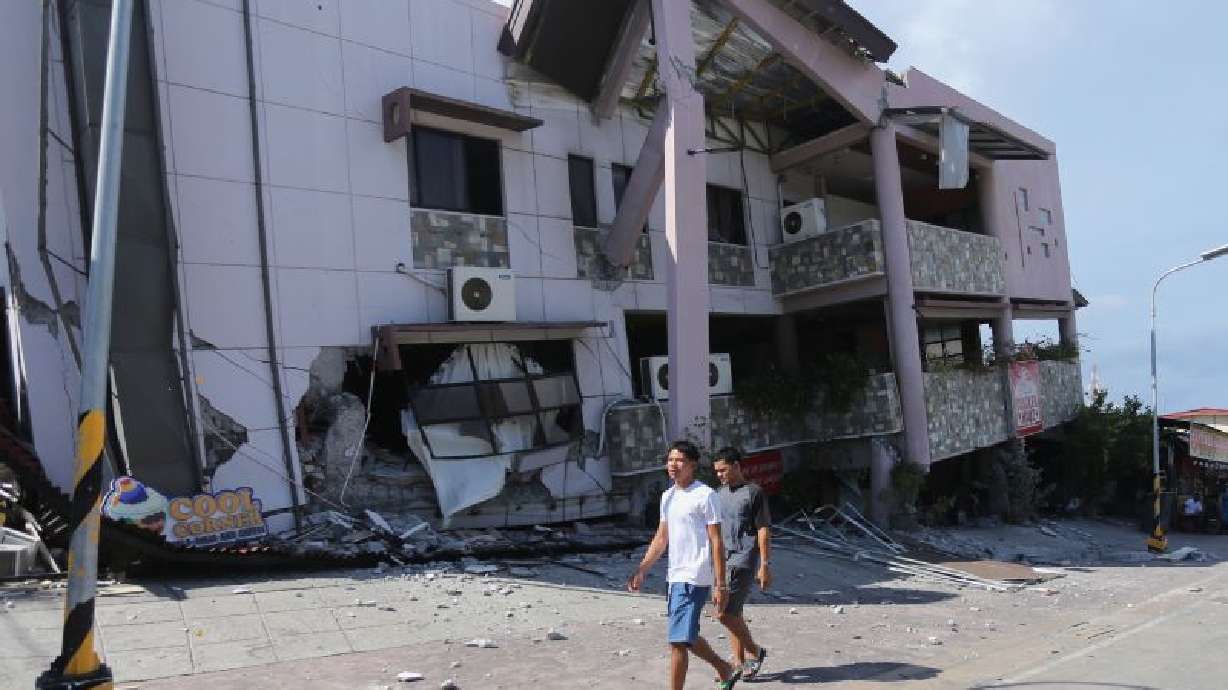 Residents pass by a collapsed structure after an earthquake in General Santos, Philippines on Monday on Monday.