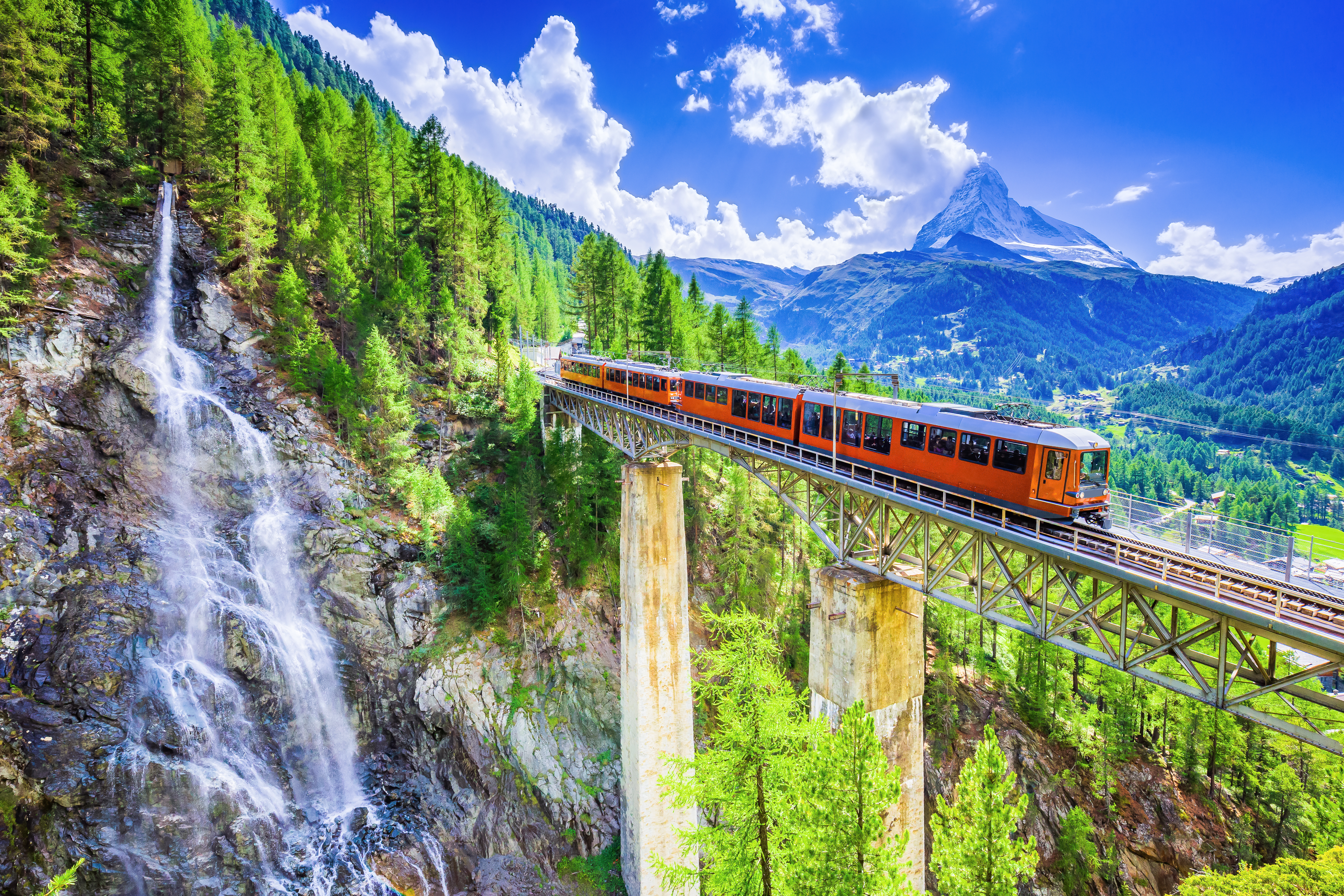 Zermatt, Switzerland. Gornergrat tourist train with waterfall, bridge and Matterhorn. Valais region.