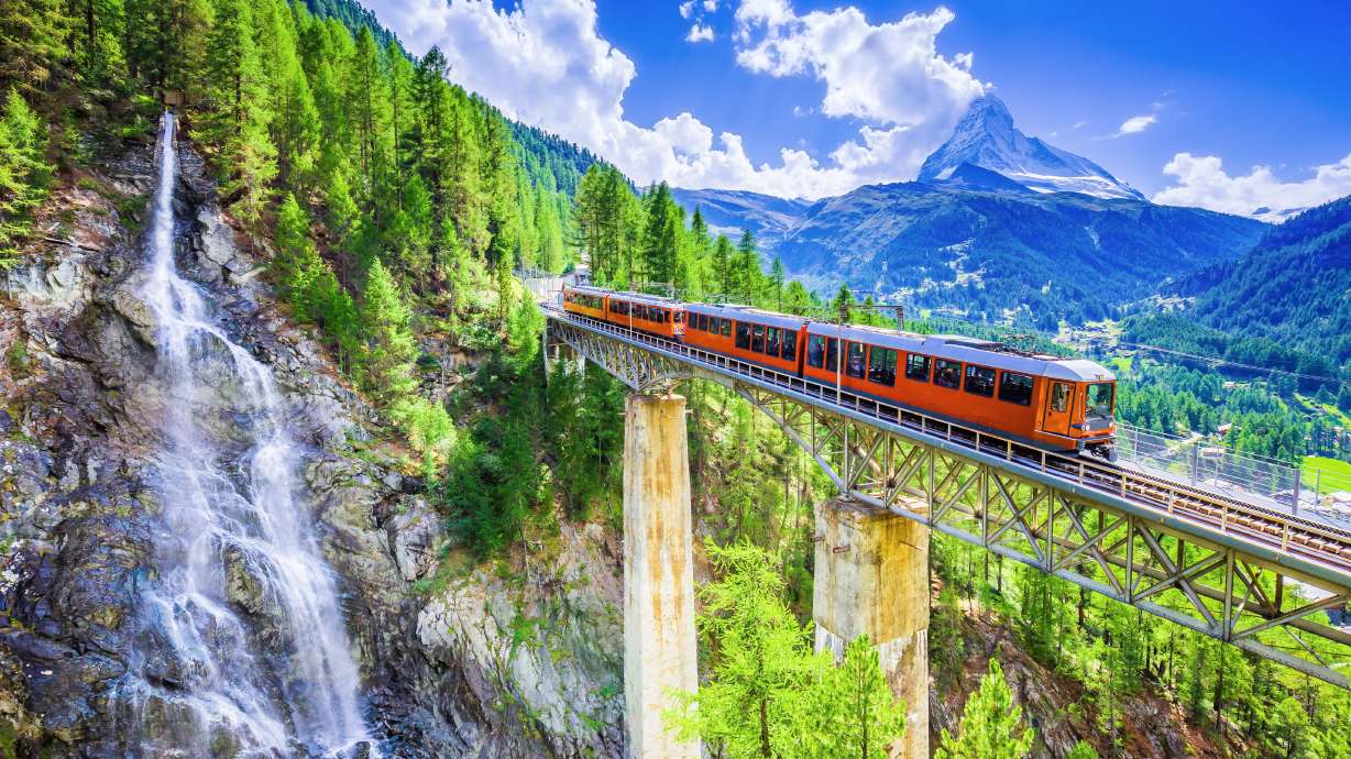 Zermatt, Switzerland. Gornergrat tourist train with waterfall, bridge and Matterhorn. Valais region.