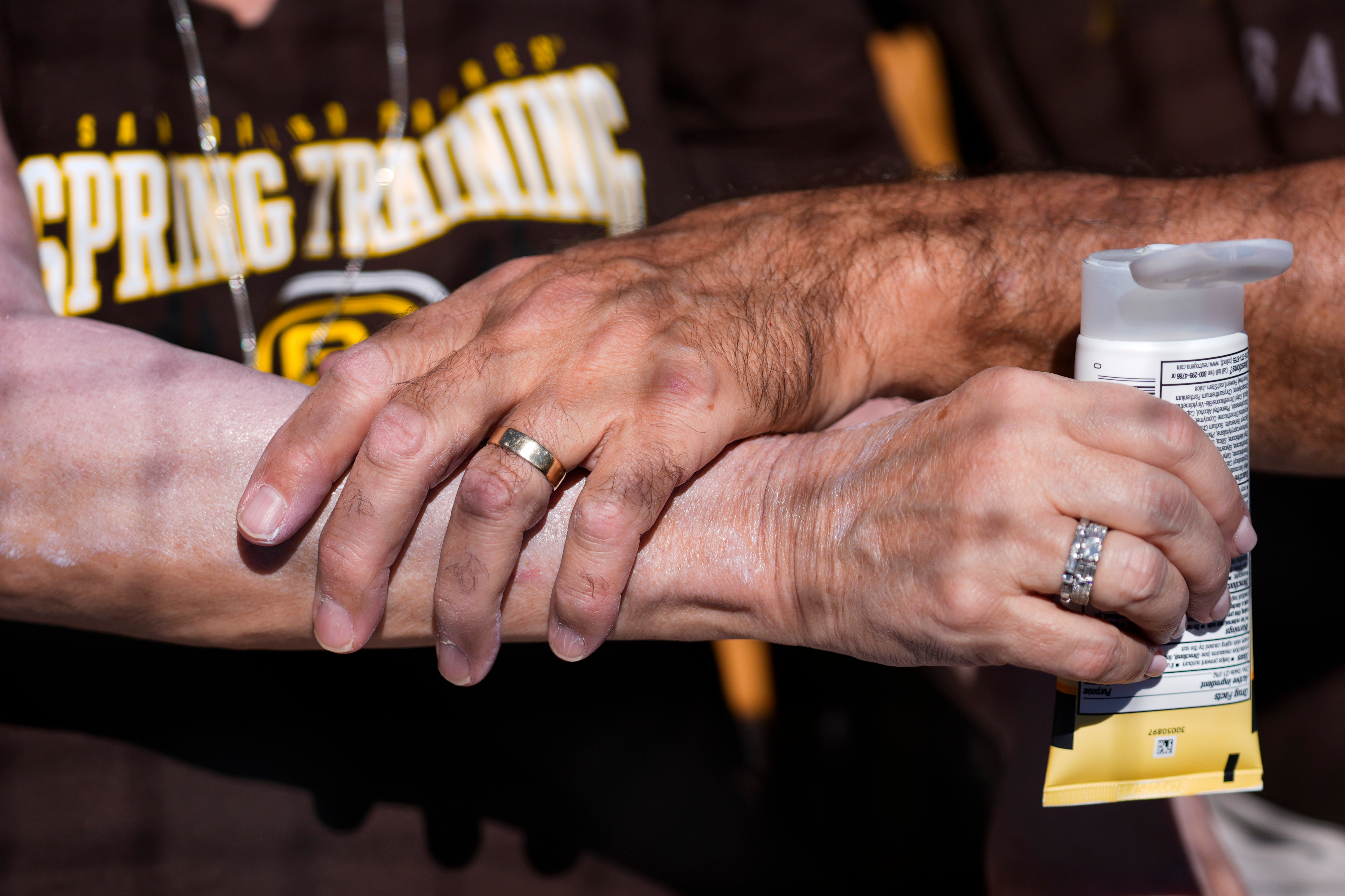 A man applies sunscreen to a woman's arm before a spring training baseball game between the San Diego Padres and the Chicago White Sox in Phoenix, Ariz., Feb. 28, 2024. A new sunscreen type, containing BEMT, hit American stores on Wednesday.
