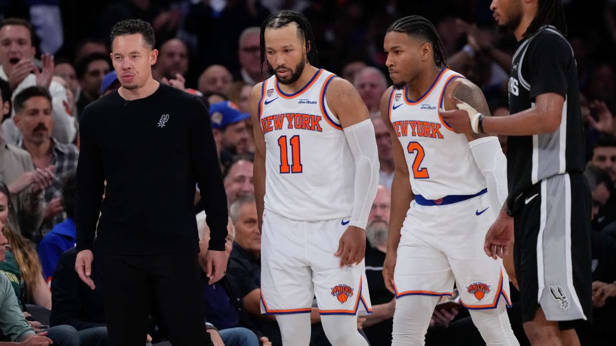 New York Knicks guard Jalen Brunson (11) and guard Miles McBride (2) walk to their bench as San Antonio Spurs head coach Mitch Johnson, left, looks away during second half of Game 3 of the NBA Finals basketball series, Monday, June 8, 2026, in New York.