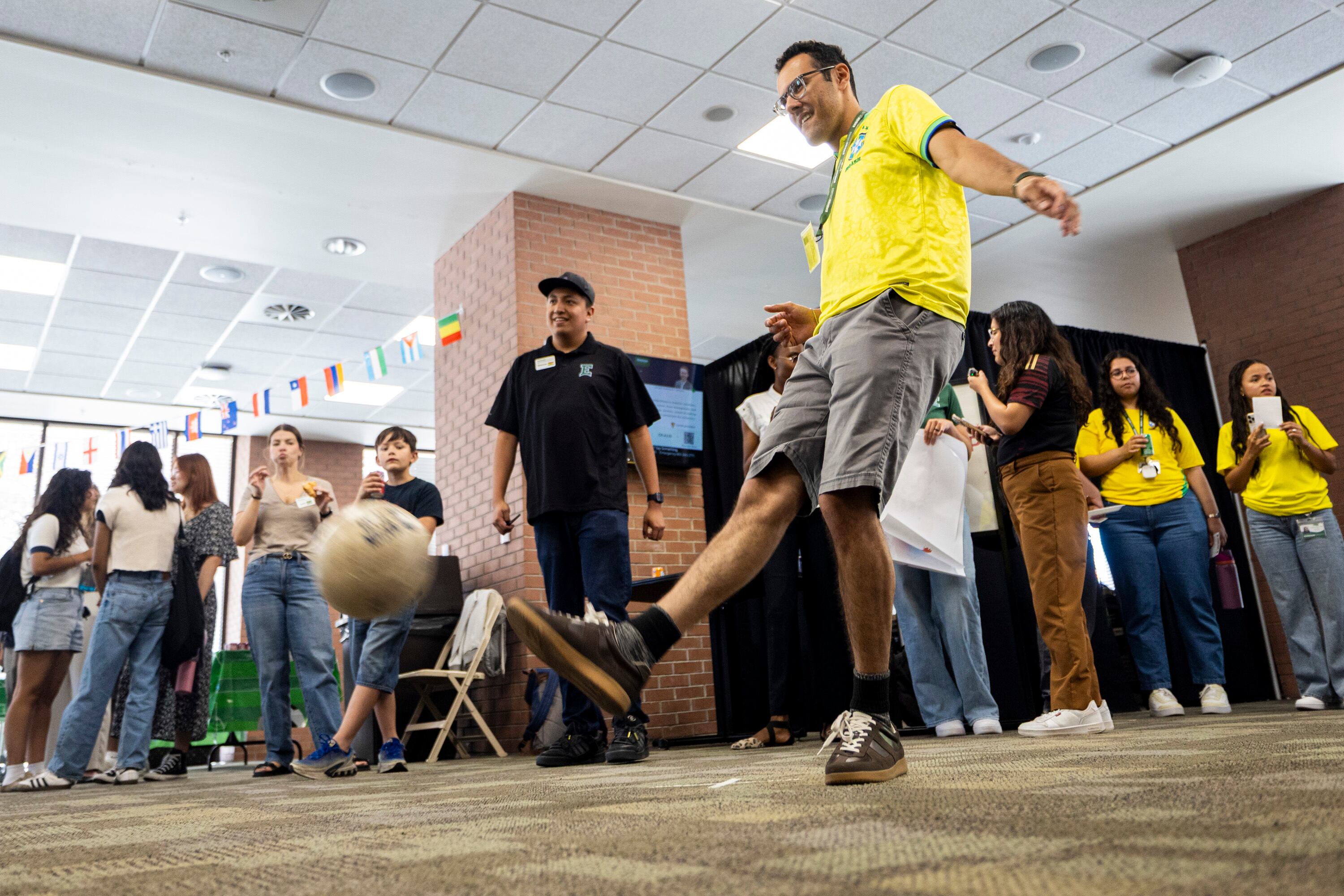 Ensign College freshman Arthur Da Silva, who is studying cyber security, kicks a soccer ball to score a goal while Spencer Garcia, who is studying software engineering, watches with other attendees during a FIFA World Cup kick-off party held at the college in Salt Lake City on Thursday. Some of the students at the school are also involved in collecting Panini World Cup stickers.