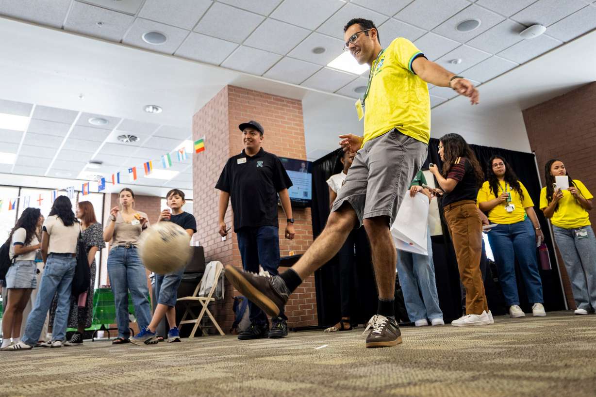Ensign College freshman Arthur Da Silva, who is studying cyber security, kicks a soccer ball to score a goal while Spencer Garcia, who is studying software engineering, watches with other attendees during a FIFA World Cup kick-off party held at the college in Salt Lake City on Thursday. Some of the students at the school are also involved in collecting Panini World Cup stickers.