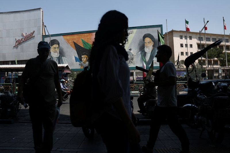 People walk past a mural depicting the late leader of the Islamic Revolution, Ayatollah Ruhollah Khomeini, and the late Iran's Supreme Leader Ayatollah Ali Khamenei, on a street in Tehran, Iran, Tuesday.