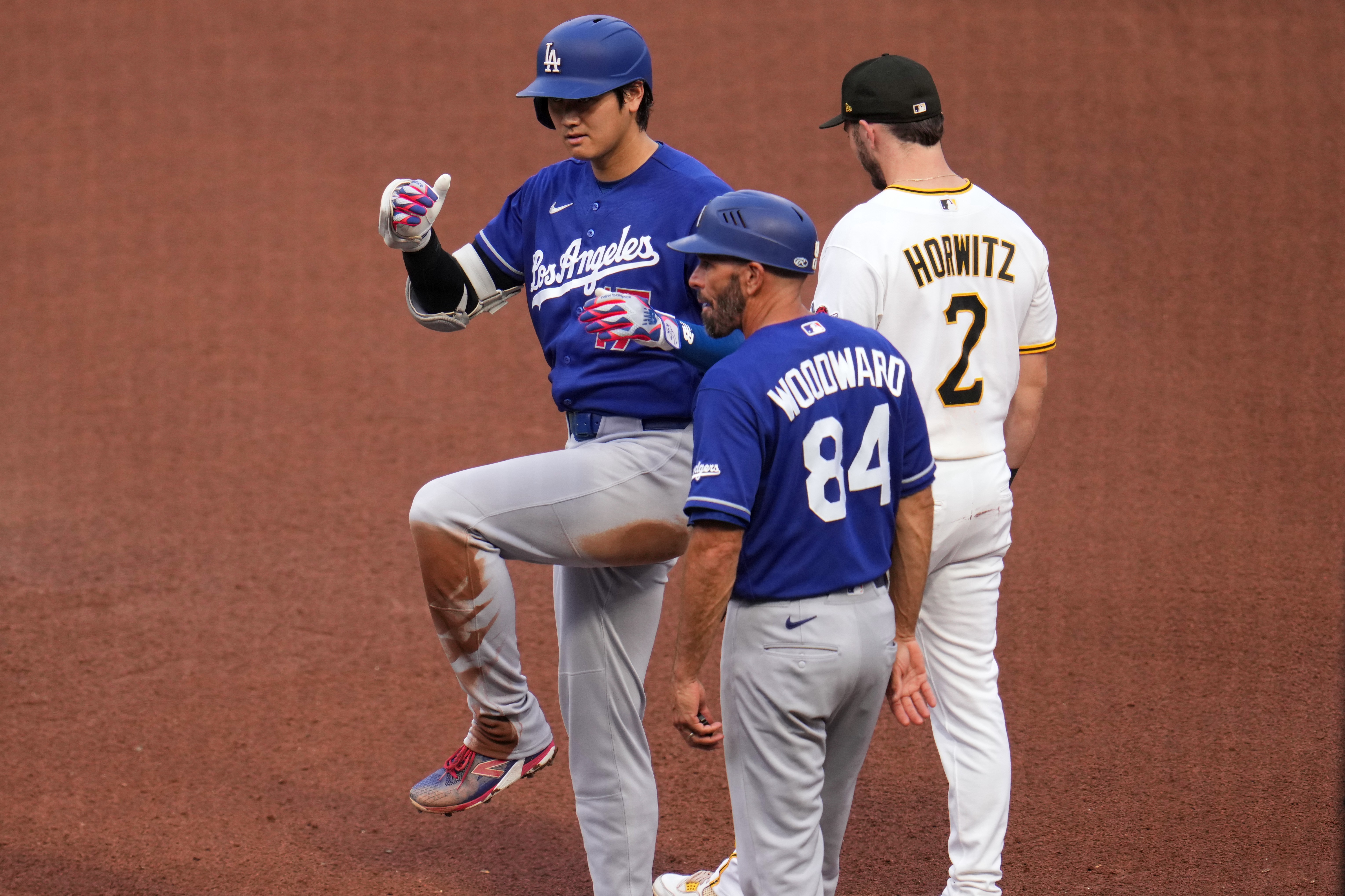Los Angeles Dodgers' Shohei Ohtani, left, celebrates as he stands on first base after hitting a single off Pittsburgh Pirates pitcher Mitch Keller during the fourth inning of a baseball game in Pittsburgh, Thursday, June 11, 2026.