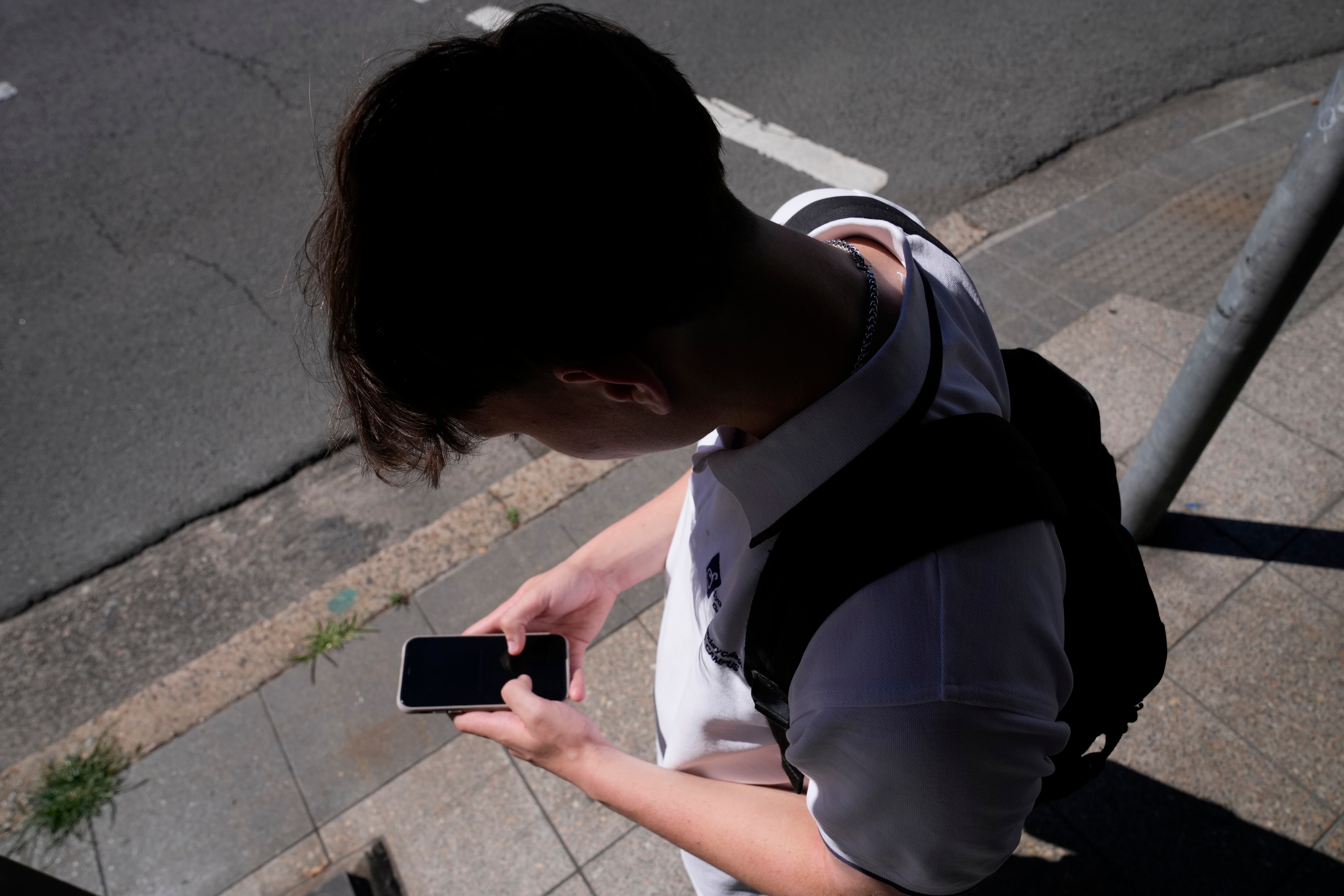 A teenage boy uses his phone in Sydney, Nov. 8, 2024. A recent report shows online violent threats against lawmakers are rising.