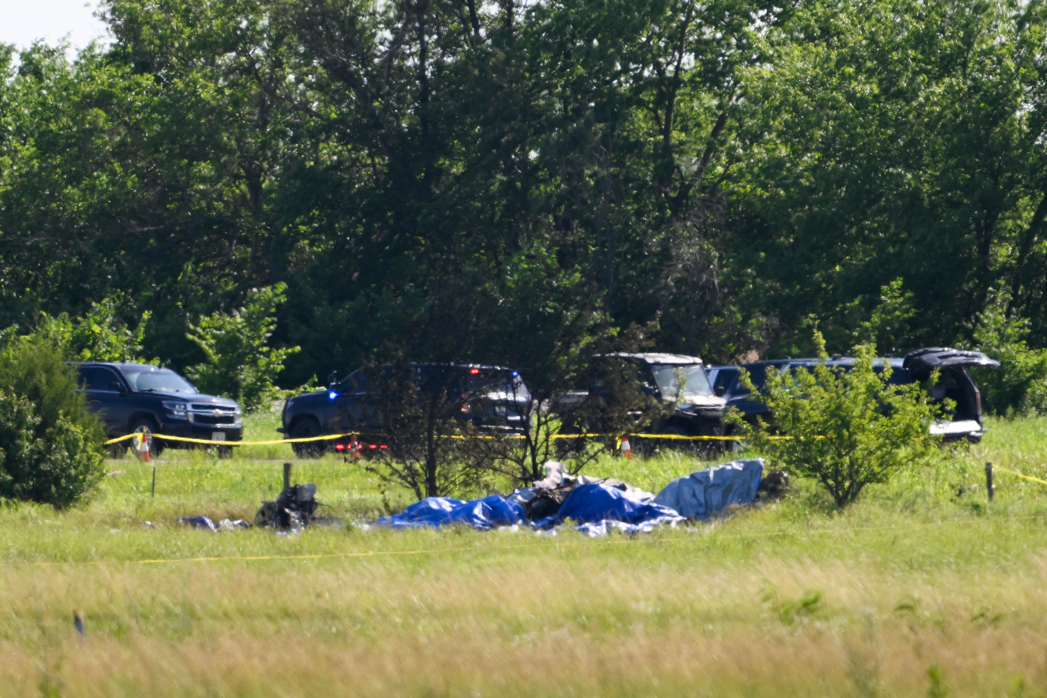 Part of the wreckage of a plane crash is covered with a blue tarp at Butler Memorial Airport in Butler, Mo., Sunday, June 14, 2026.