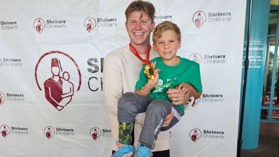 Zach Adler poses for a picture with Paralympic Gold medalist Hunter Woodhall, who was born with the same condition as Zach, only in both of his legs.
