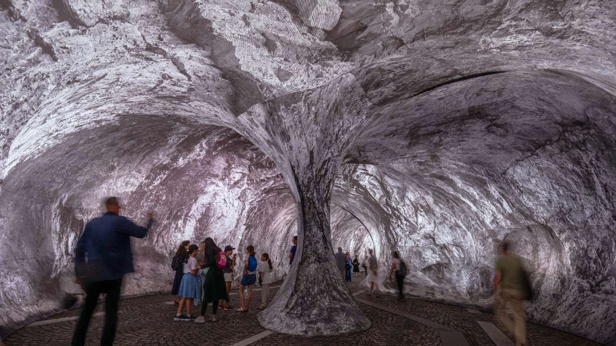 Visitors walk into the artwork "The Pont Neuf Cave" by French street artist JR on the Pont Neuf bridge, Tuesday, in Paris, open to the public from Monday till June 28. The exhibit opened on Monday night.