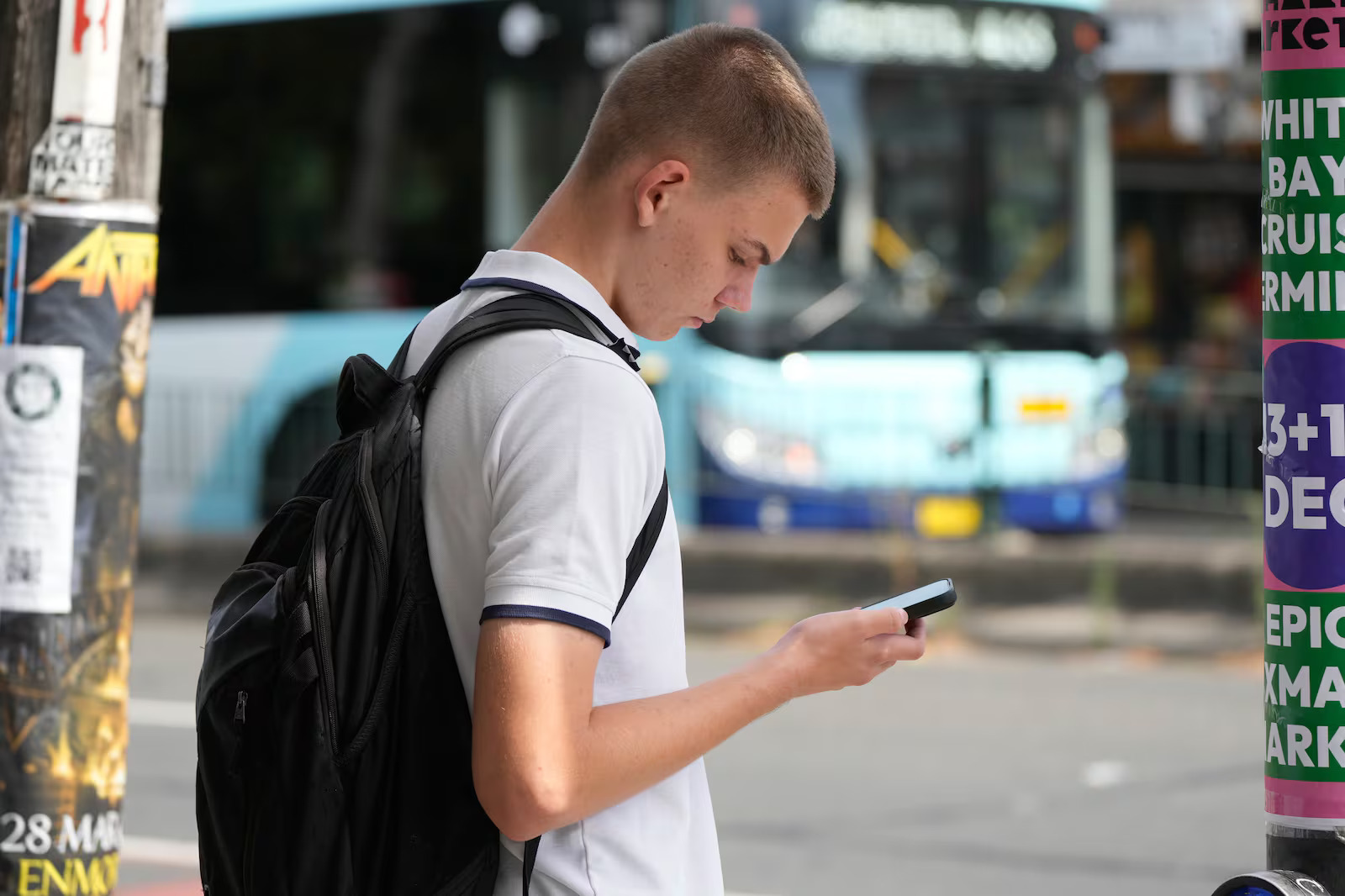 School boy Kyryl Pantovic uses his phone as he waits to cross the street in Sydney, Australia, Monday. Australia and the U.K. both enacted social media bans for youths under 16.