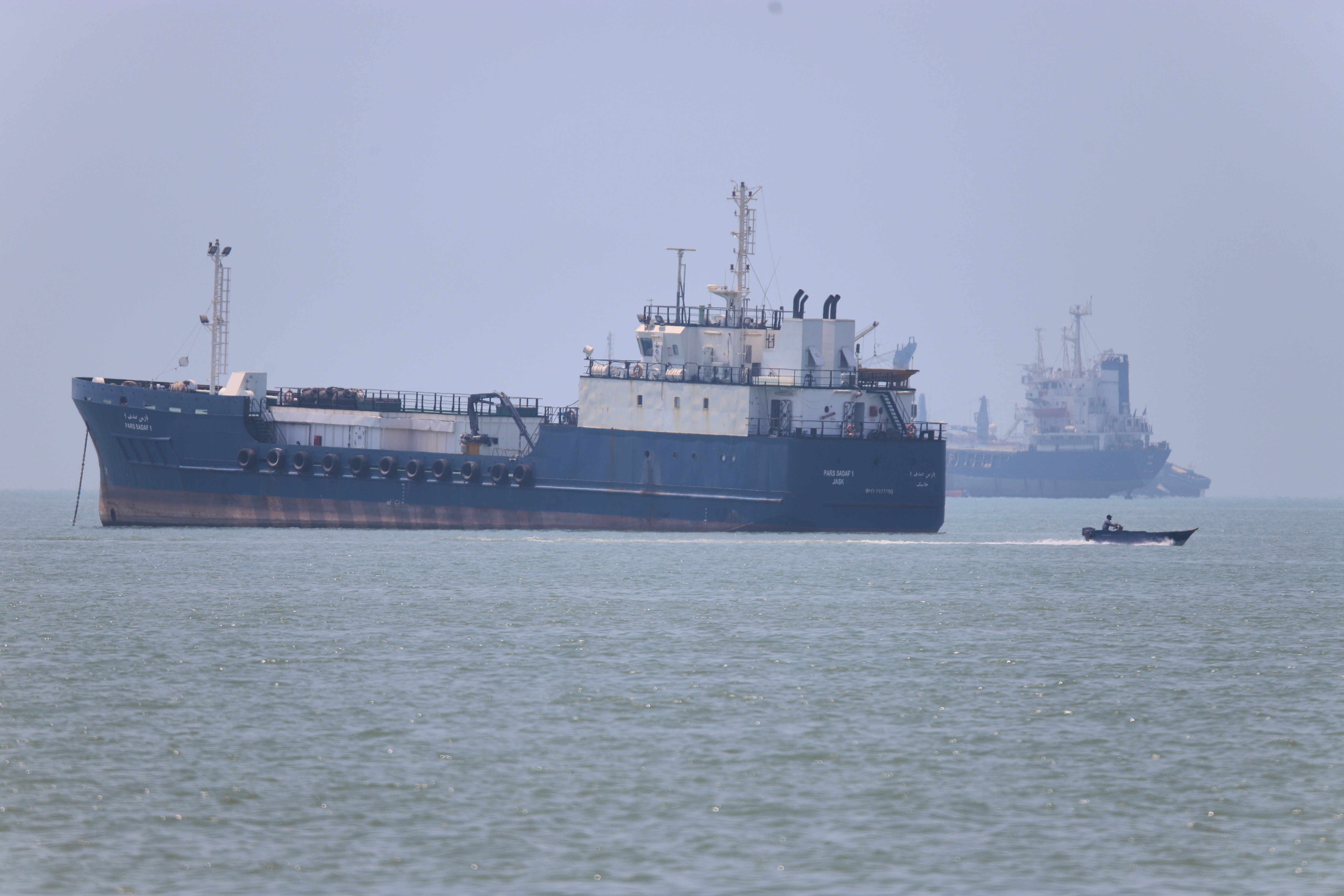 A small motorboat passes anchored vessels in the Strait of Hormuz off Bandar Abbas, Iran, Wednesday. Cargo ships began transiting the strait on Thursday as a tentative deal to end the war in Iran took effect.