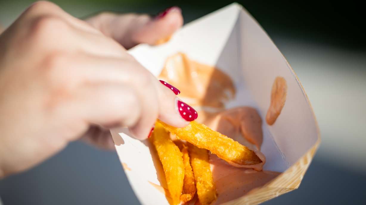 Saige Clawson, from Farmington, samples different fry sauces from Utah businesses at Fry Sauce Night during a Salt Lake Bees game against the Tacoma Rainiers at The Ballpark at America First Square in South Jordan on Thursday.