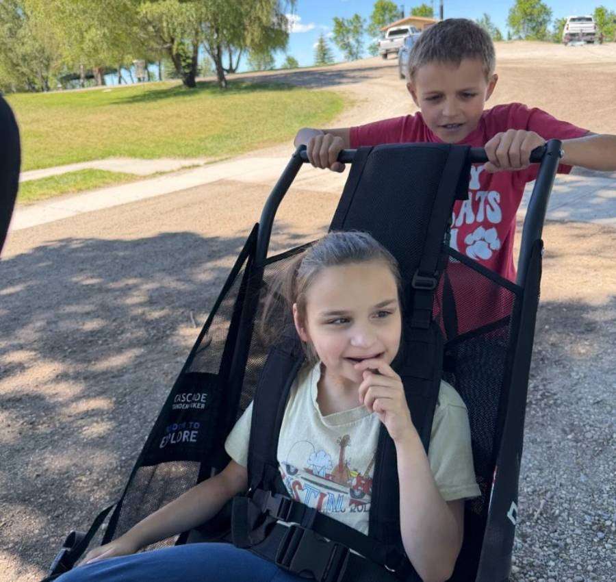 Jackson Goodsell pushes his sister Hailey in her new Huckleberry Hiking outdoor mobility chair at Beaver Dick Park in Madison County, Idaho.