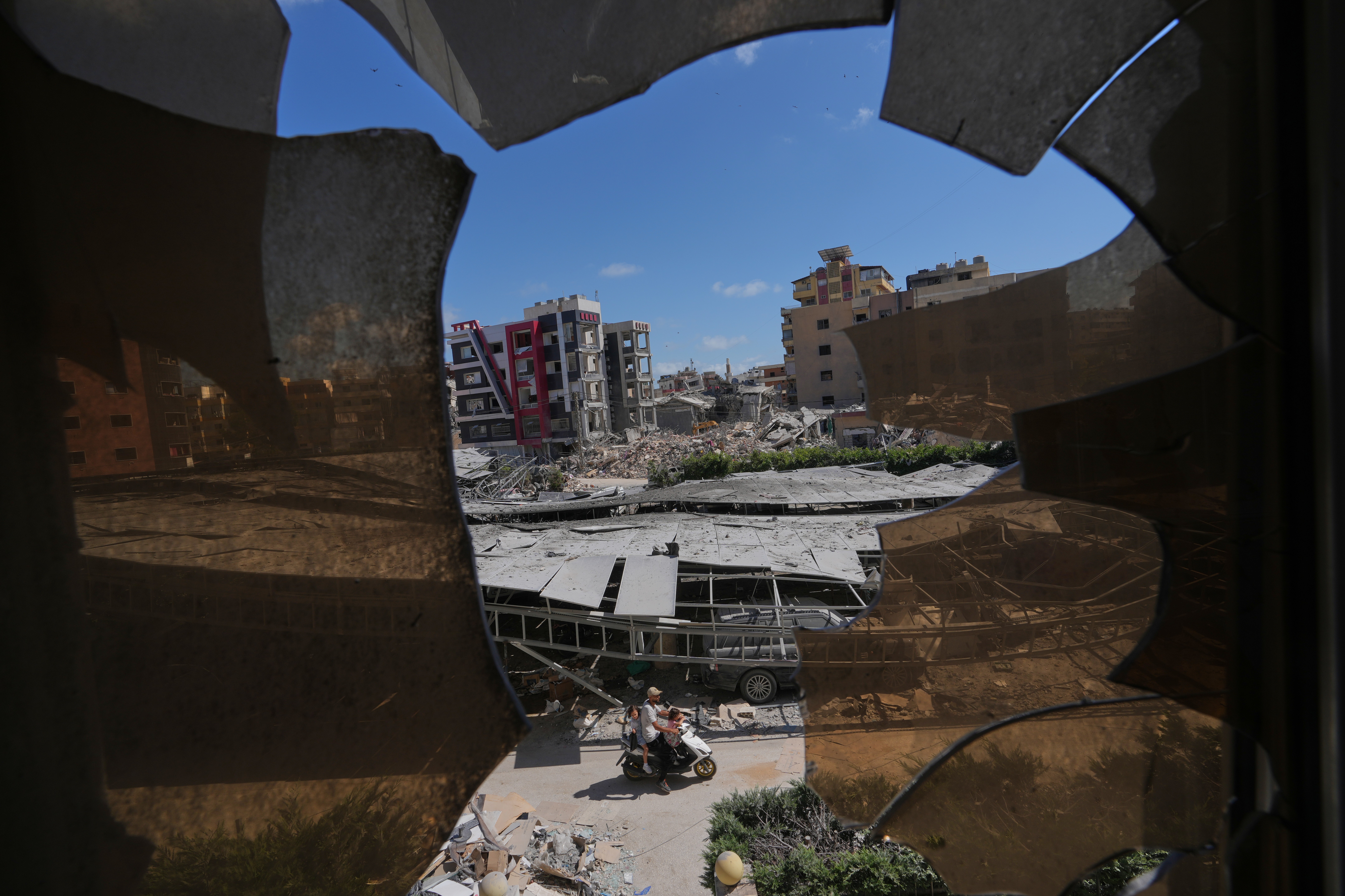Buildings damaged by Israeli strikes are seen through shattered glass from the Jabal Amel Hospital in the southern port city of Tyre, Lebanon, Thursday. Increased fighting in Lebanon has threatened an interim agreement to end the war in Iran.