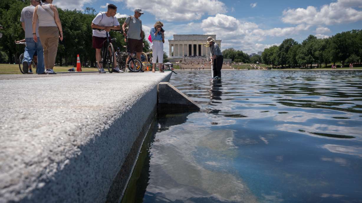 A National Park Service employee uses a vacuum to clean the Lincoln Memorial Reflecting Pool near a missing section of blue coating, Friday, in Washington. President Donald Trump is alleging that the peeling is due to vandalism.