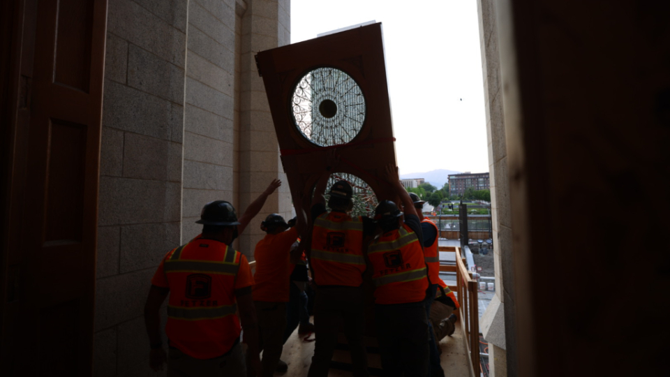A crew of at least eight construction workers raises a side of the east temple doors during its reinstallment Tuesday at the Salt Lake Temple.