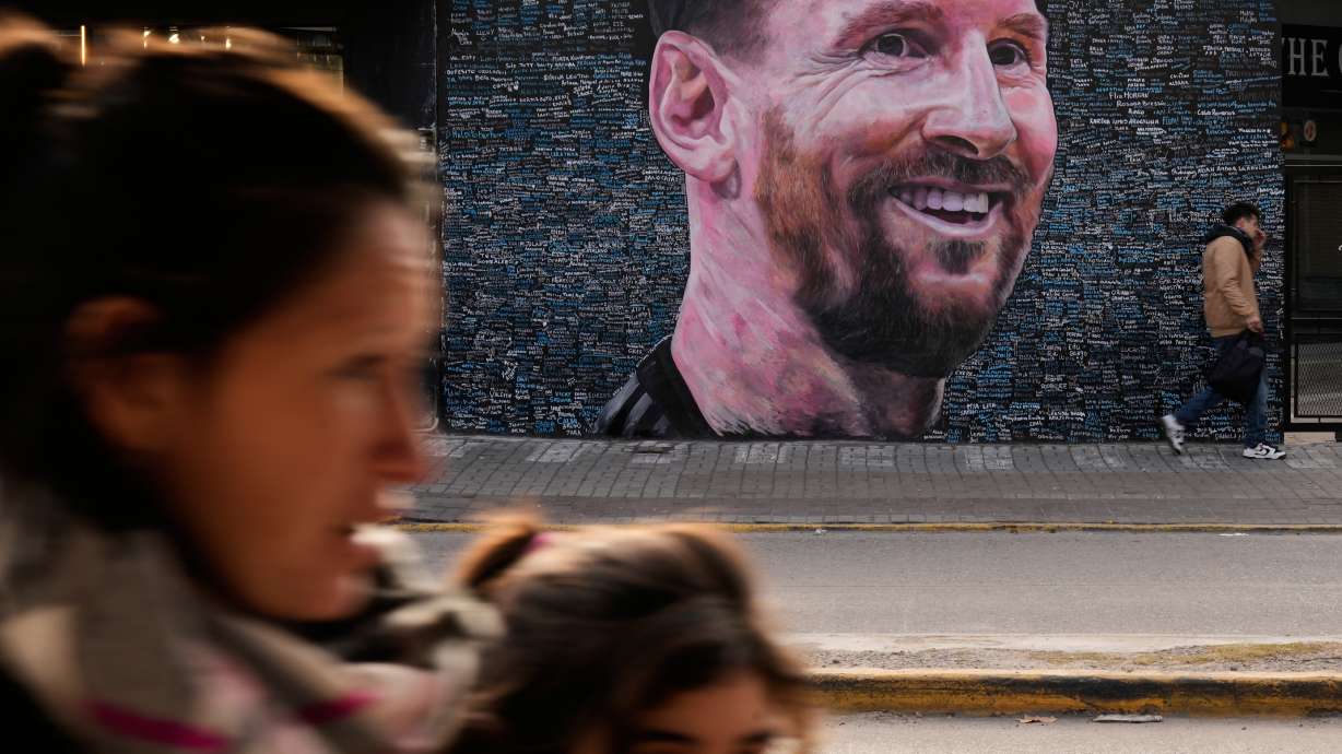 People walk past a mural of Lionel Messi by artist Leonel Garcia, which includes the names of local residents inscribed by them as a tribute to the soccer star, in Berazategui, on the outskirts of Buenos Aires, Argentina, Monday, June 22, 2026.