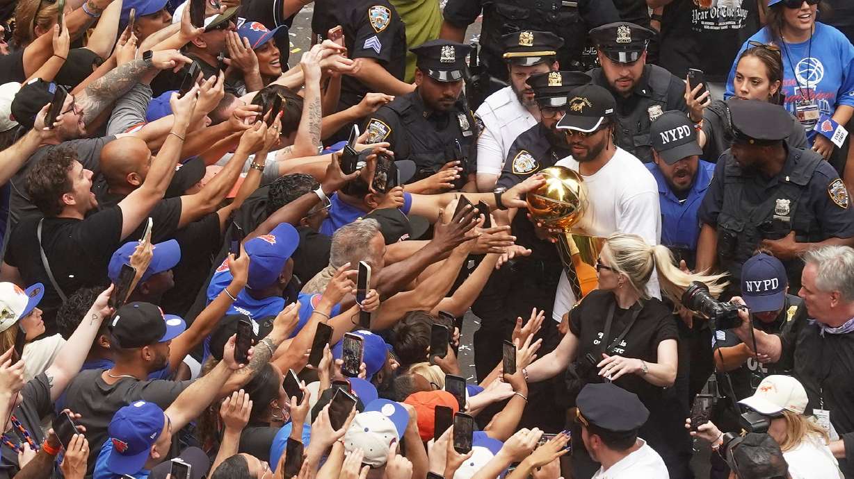 Jalen Brunson, upper right, of the NBA Champion New York Knicks carries the trophy for fans during the ticker-tape parade on Broadway, in New York's "Canyon of Heroes," Thursday, June 18, 2026.