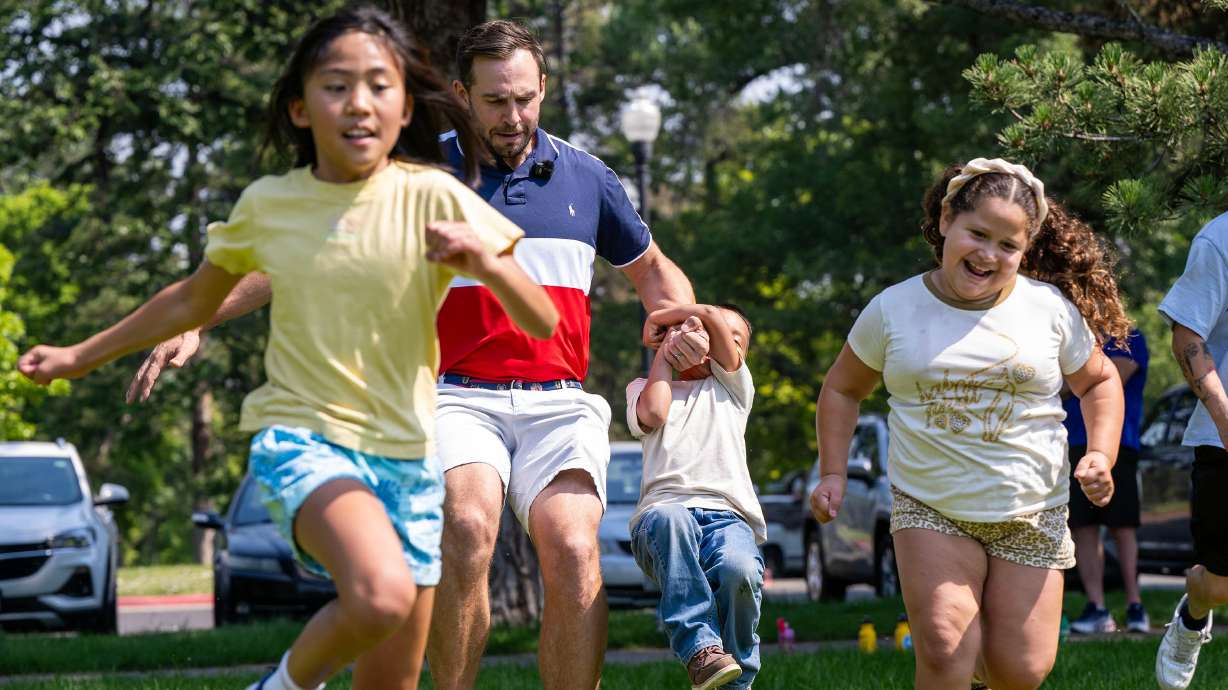 Eevie and Yajhandra run while Chris Mazdzer, luge, carries Jacob on his arm as Olympic and Paralympic athletes from the 2026 Milan Cortina Winter Games celebrate global Olympic Day at Liberty Park in Salt Lake City on Tuesday.