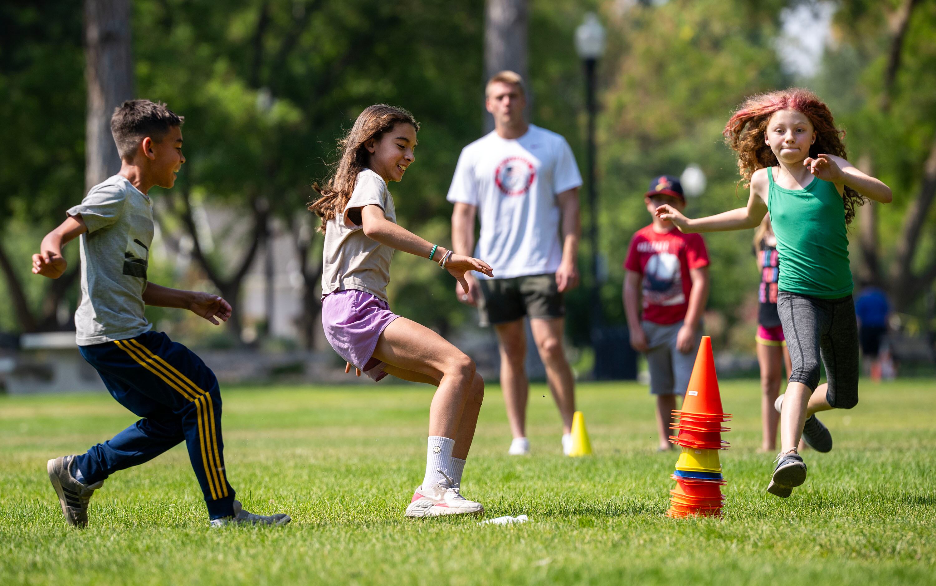 Jesse, Gianah and Hazel race to grab small orange cones as they join Olympic and Paralympic athletes from the 2026 Milan Cortina Winter Games to celebrate global Olympic Day with a morning of workouts with the kids at Salt Lake City’s YouthCity program at Liberty Park in Salt Lake City on Tuesday, June 23, 2026. Olympic Day is an annual global celebration of sport that promotes healthy and active lifestyles. It commemorates the founding of the International Olympic Committee in 1894, the start of the modern Olympic Games.