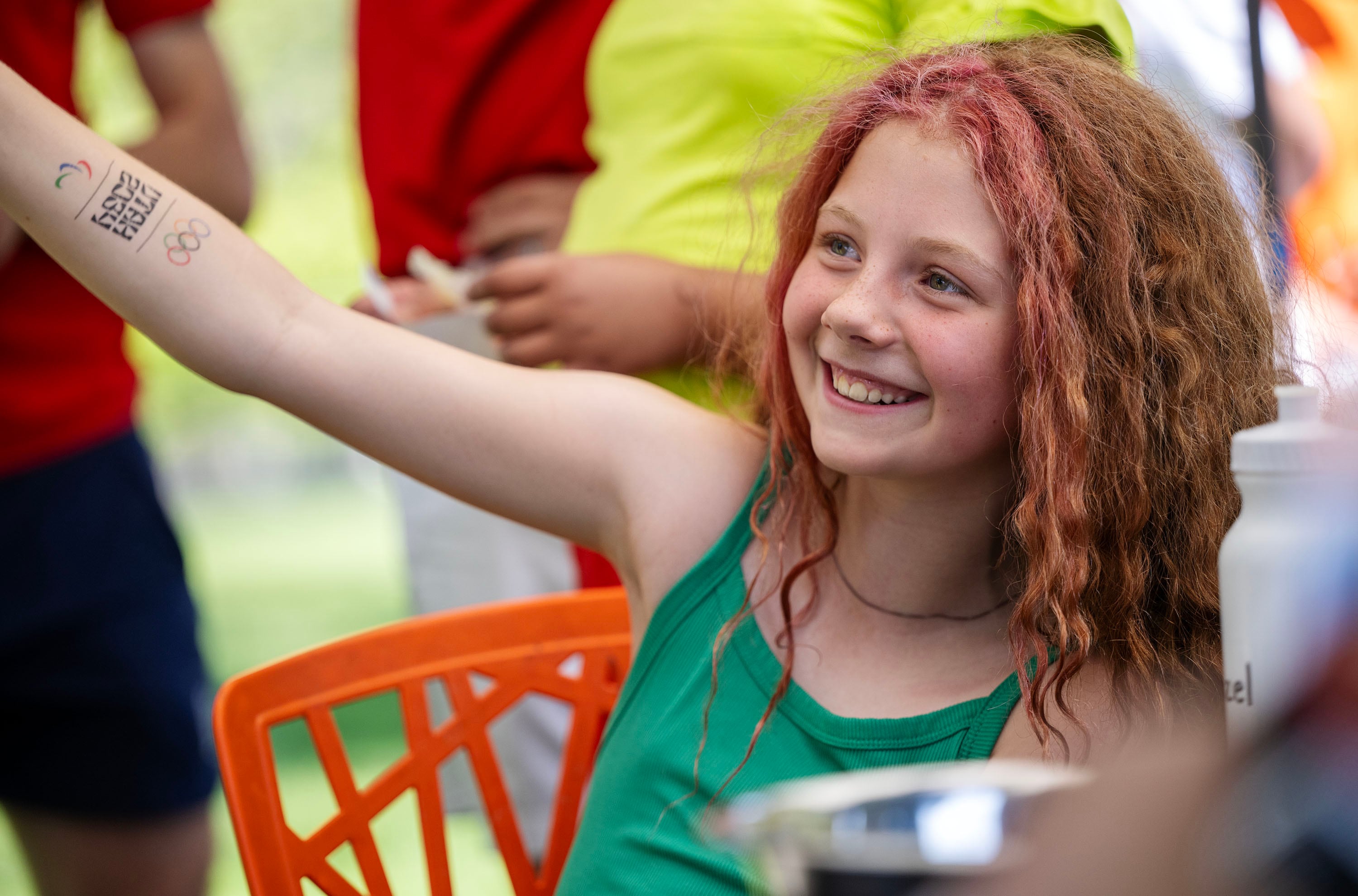 Hazel smiles as she shows off her new temporary Olympic tattoo as she joins Olympic and Paralympic athletes from the 2026 Milan Cortina Winter Games in celebrating global Olympic Day with a morning of workouts with other kids at Salt Lake City’s YouthCity program at Liberty Park in Salt Lake City on Tuesday.