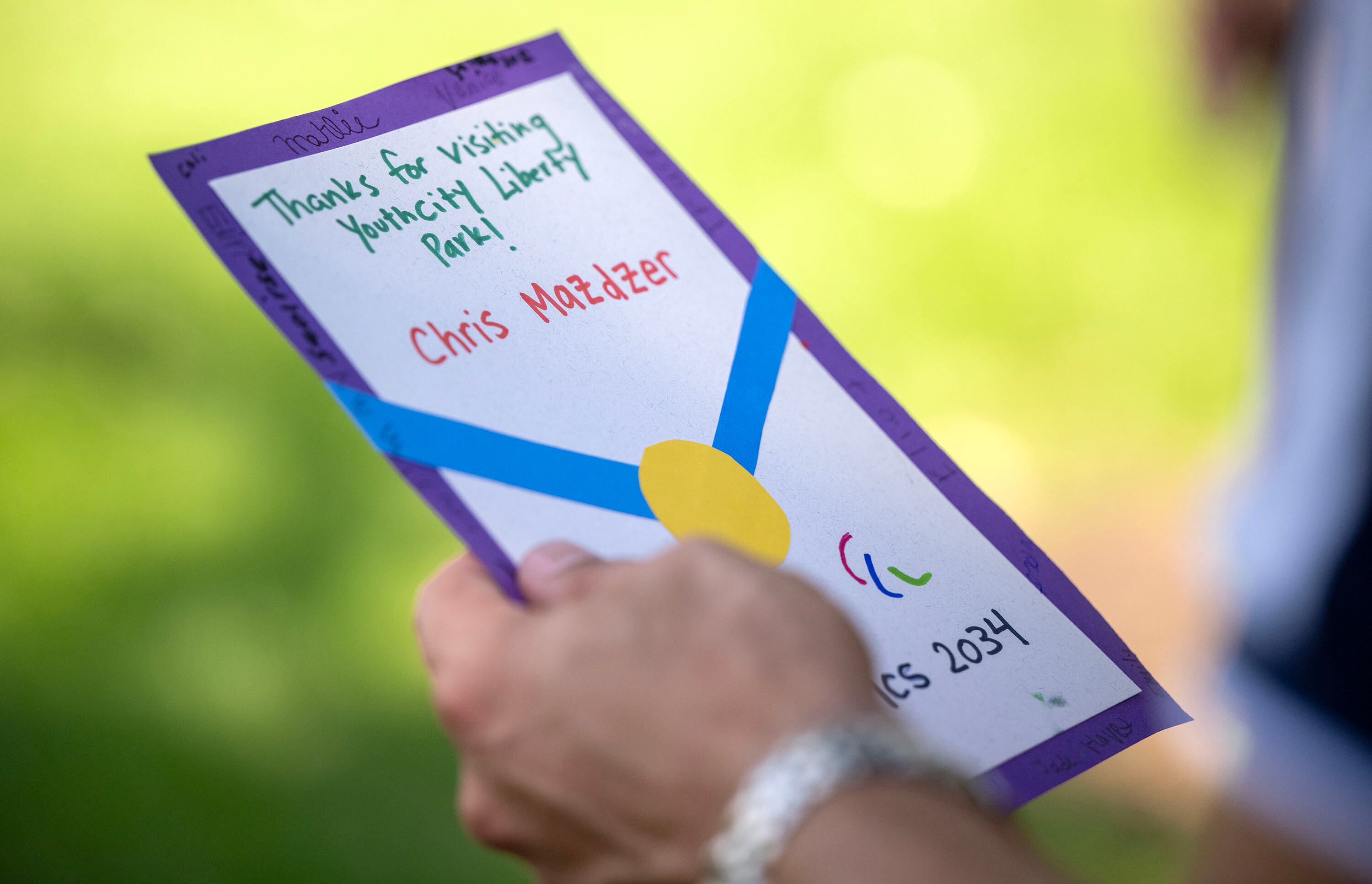 Chris Mazdzer, luge, looks at a card that was given to him from the kids, thanking the Olympic and Paralympic athletes from the 2026 Milano Cortina Winter Games for coming to celebrate global Olympic Day with a morning of workouts with the kids at Salt Lake City’s YouthCity program at Liberty Park in Salt Lake City on Tuesday.