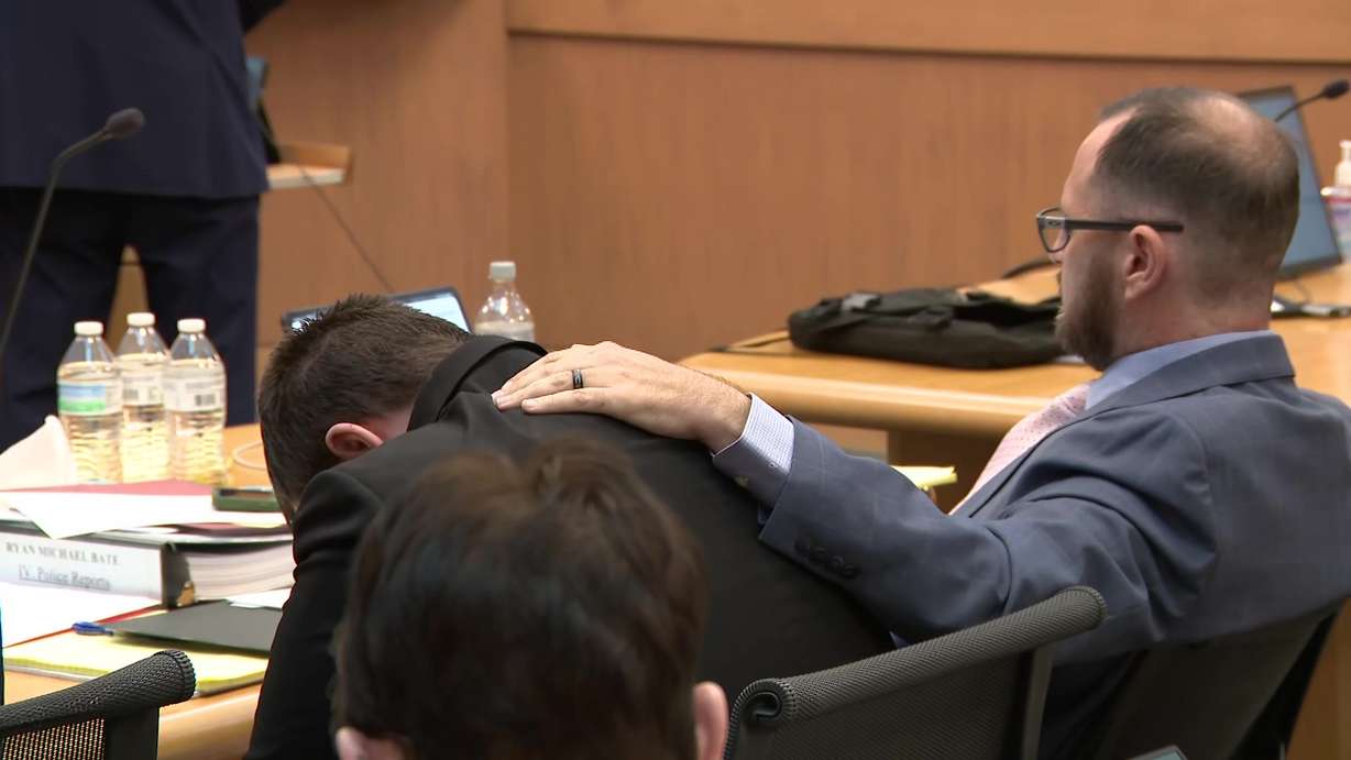 Defense attorney Jonathan Nish places his hand on the back of his client Ryan Michael Bate, who is accused of killing two Tremonton cops during a domestic violence response in August 2025, during a hearing Wednesday.