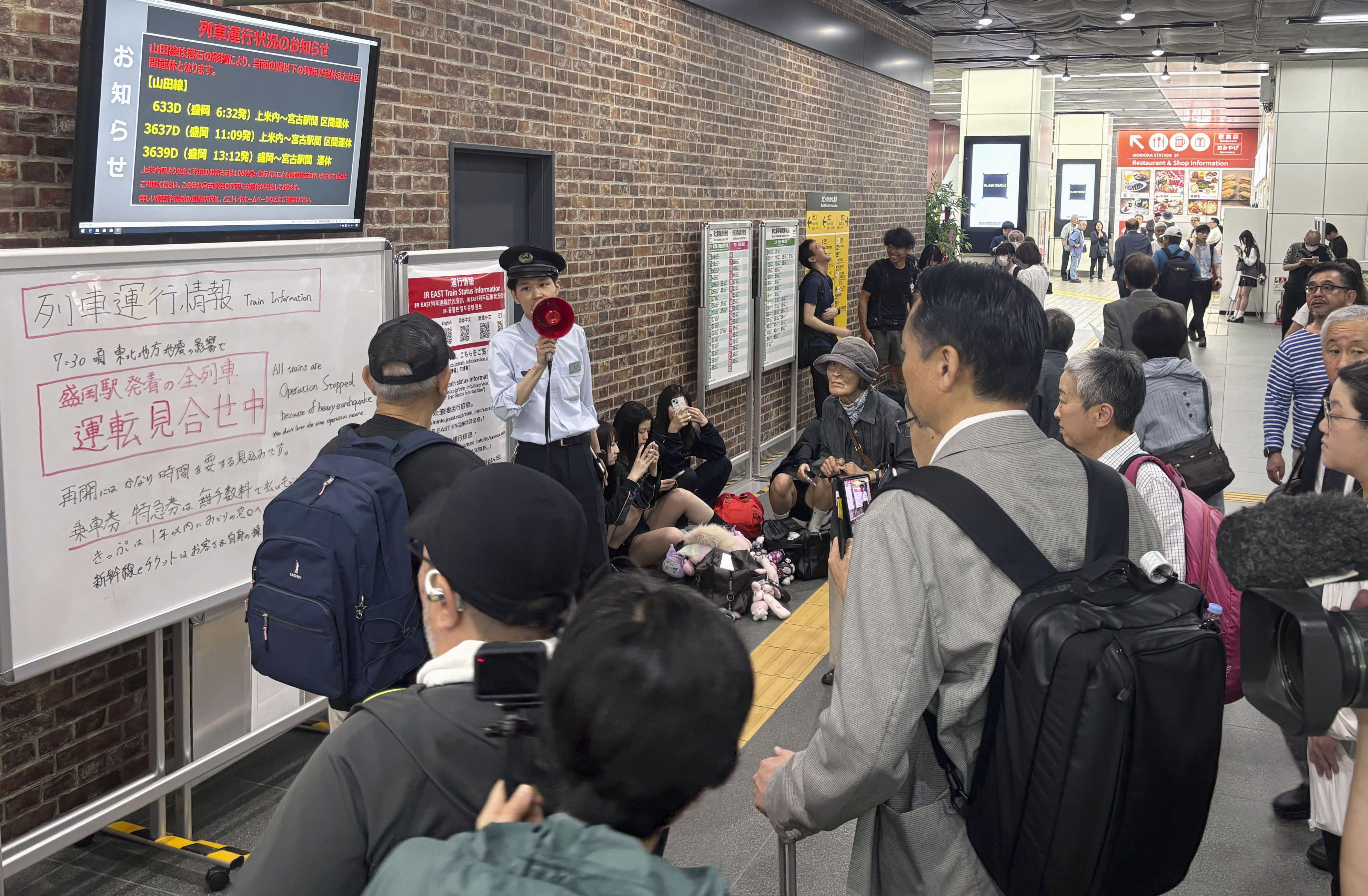 A station clerk of the East Japan Railway Co., provides an update about train services which were suspended due to an earthquake at JR Morioka station in Morioka, northern Japan, Wednesday.