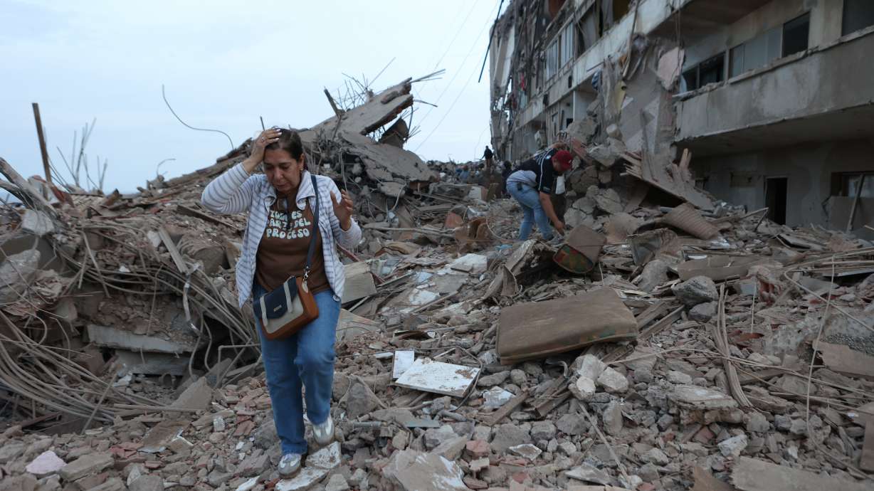 Residents walk among the rubble of building damaged in earthquakes the previous day in Catia La Mar, Venezuela, Thursday. Officials said the quakes have killed at least 188 and have trapped over 200 more.